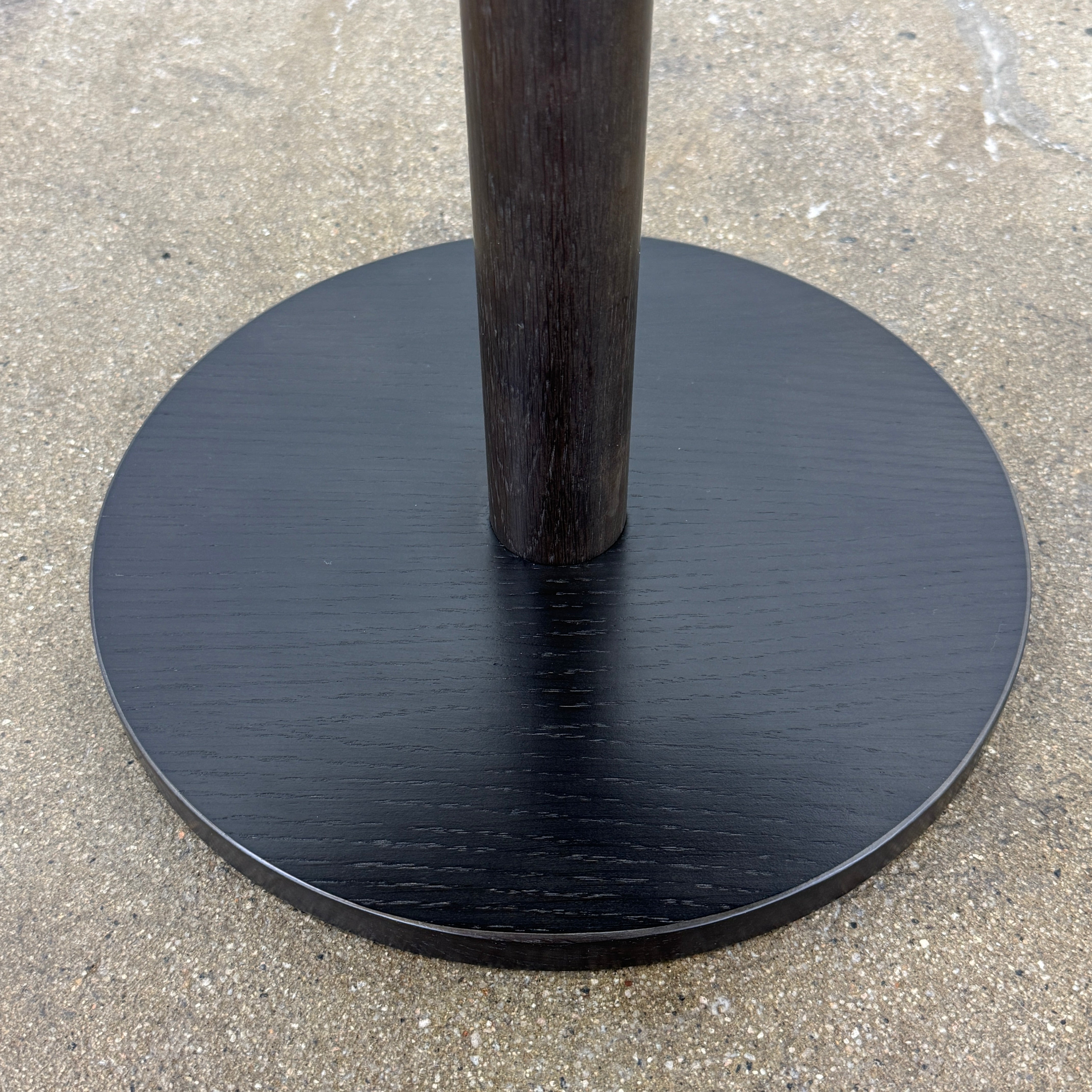 The Maruni Hiroshima Side Table by Maruni features a small, round black oak top and a single central pedestal base, shown against a plain light gray background.
