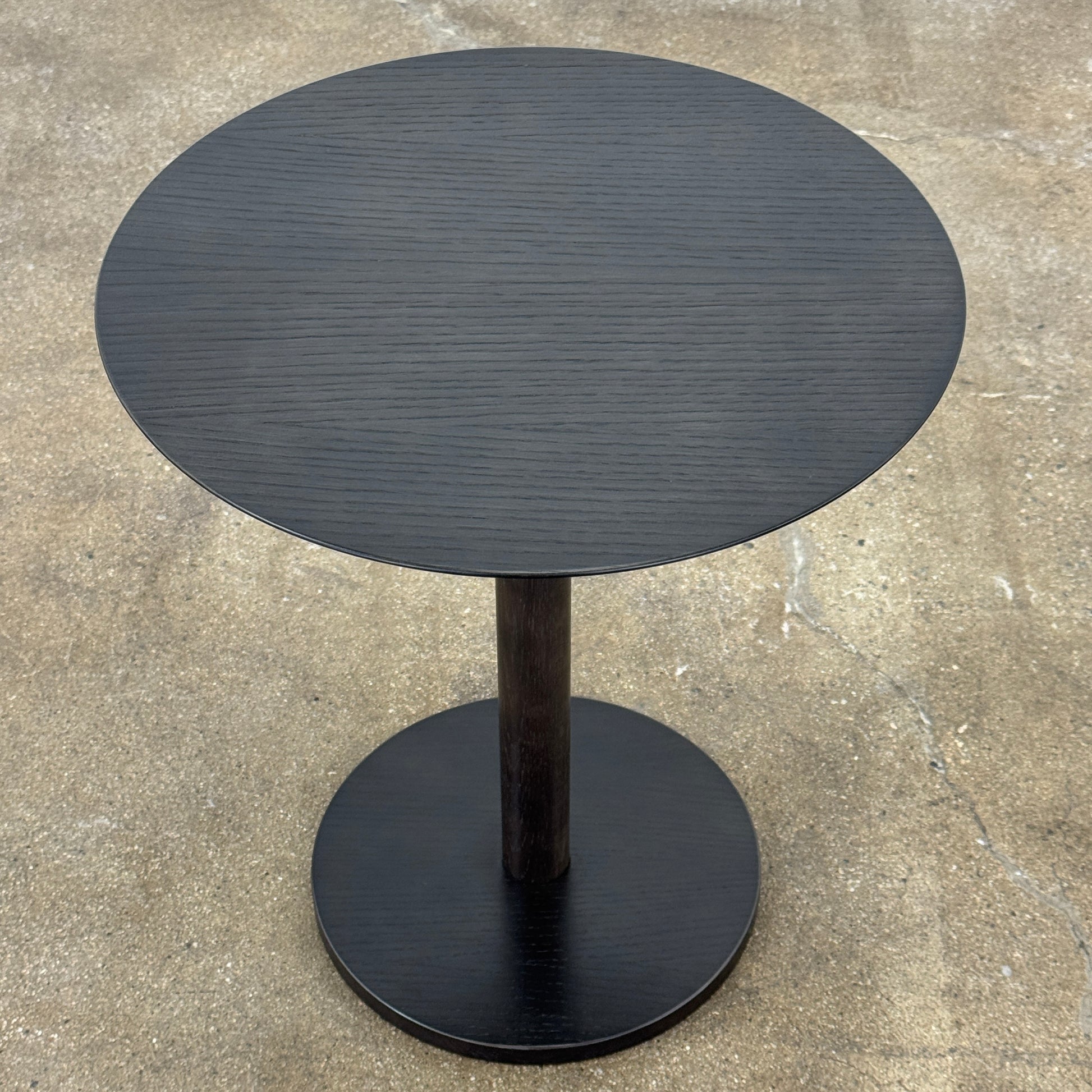 The Maruni Hiroshima Side Table by Maruni features a small, round black oak top and a single central pedestal base, shown against a plain light gray background.