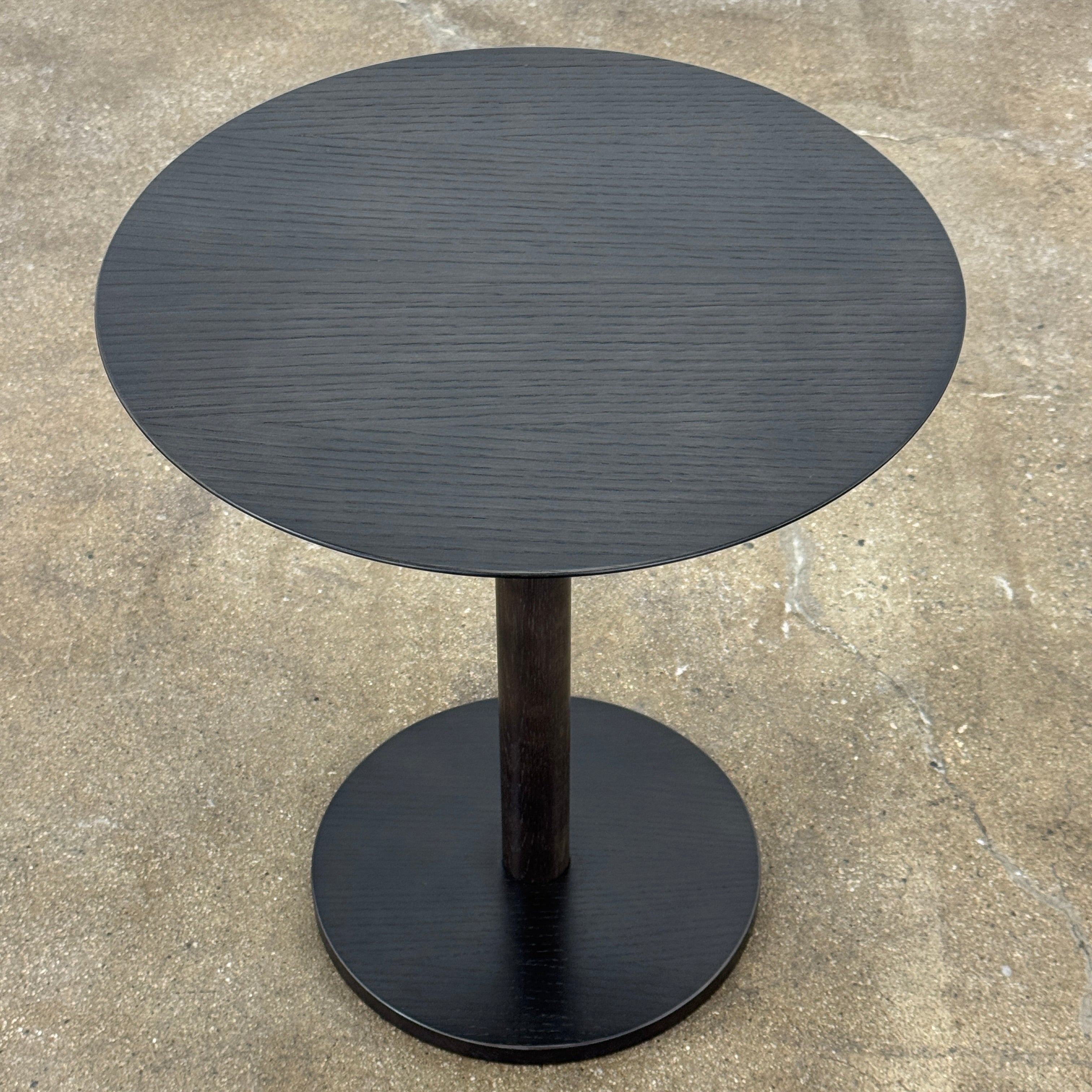 The Maruni Hiroshima Side Table by Maruni features a small, round black oak top and a single central pedestal base, shown against a plain light gray background.