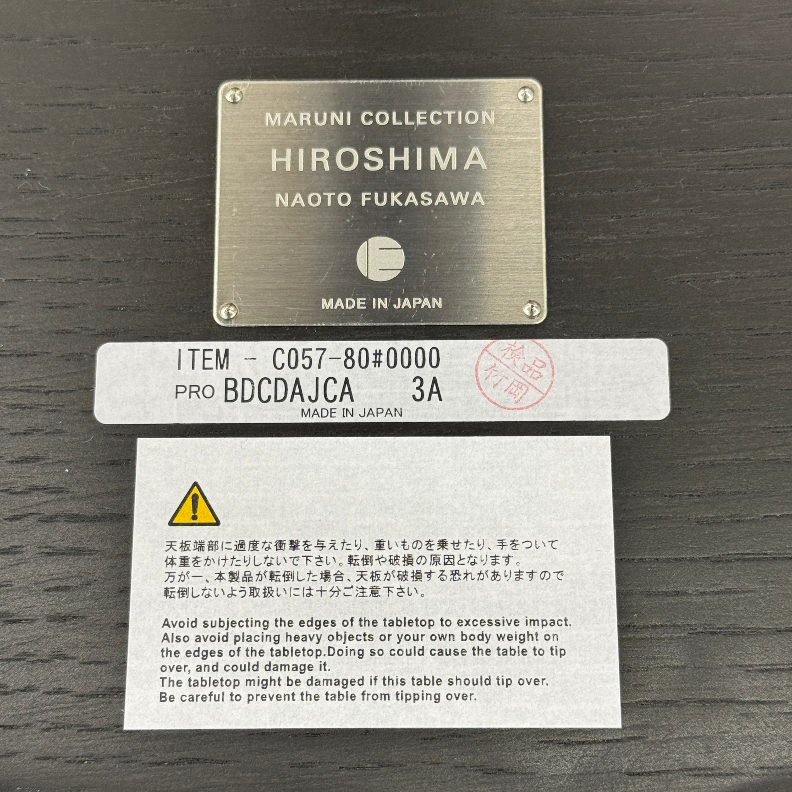 The Maruni Hiroshima Side Table by Maruni features a small, round black oak top and a single central pedestal base, shown against a plain light gray background.