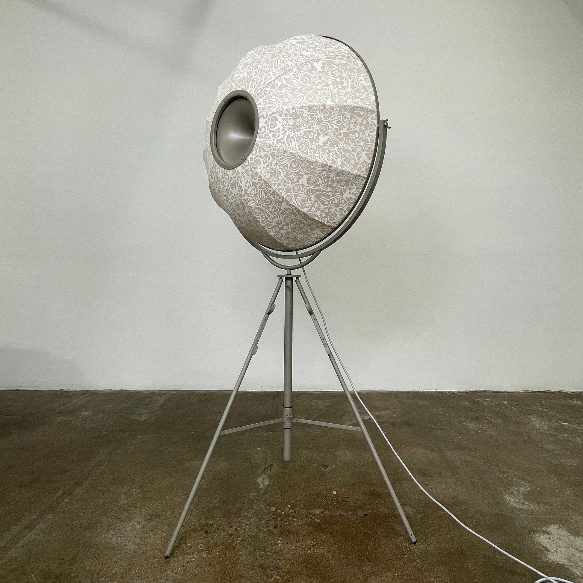 The Pallucco Italia Fortuny Ornament Floor Lamp, with its visible bulb and patterned spherical shade, gracefully stands on a plain white background, epitomizing the elegance of Pallucco Italia.