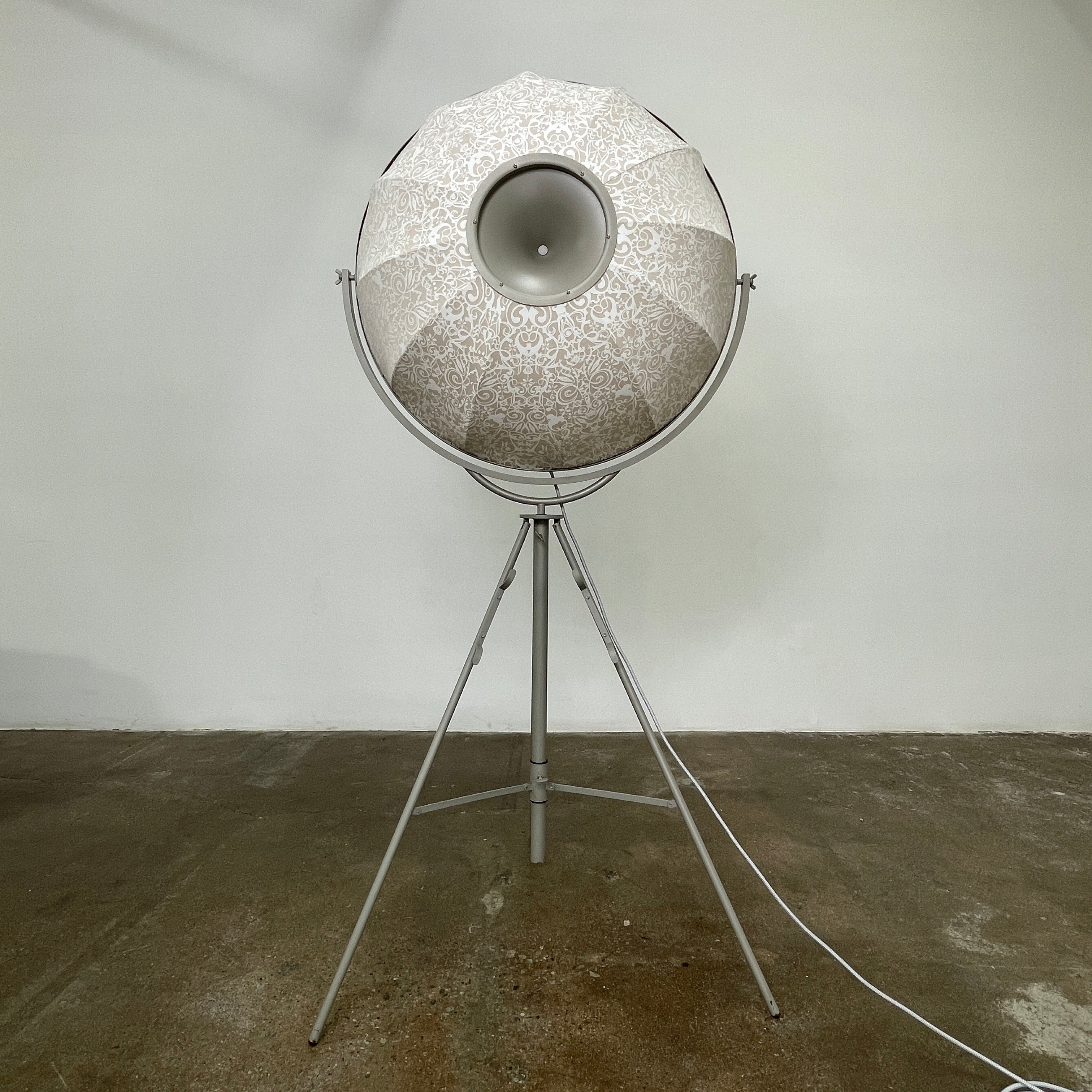 The Pallucco Italia Fortuny Ornament Floor Lamp, with its visible bulb and patterned spherical shade, gracefully stands on a plain white background, epitomizing the elegance of Pallucco Italia.