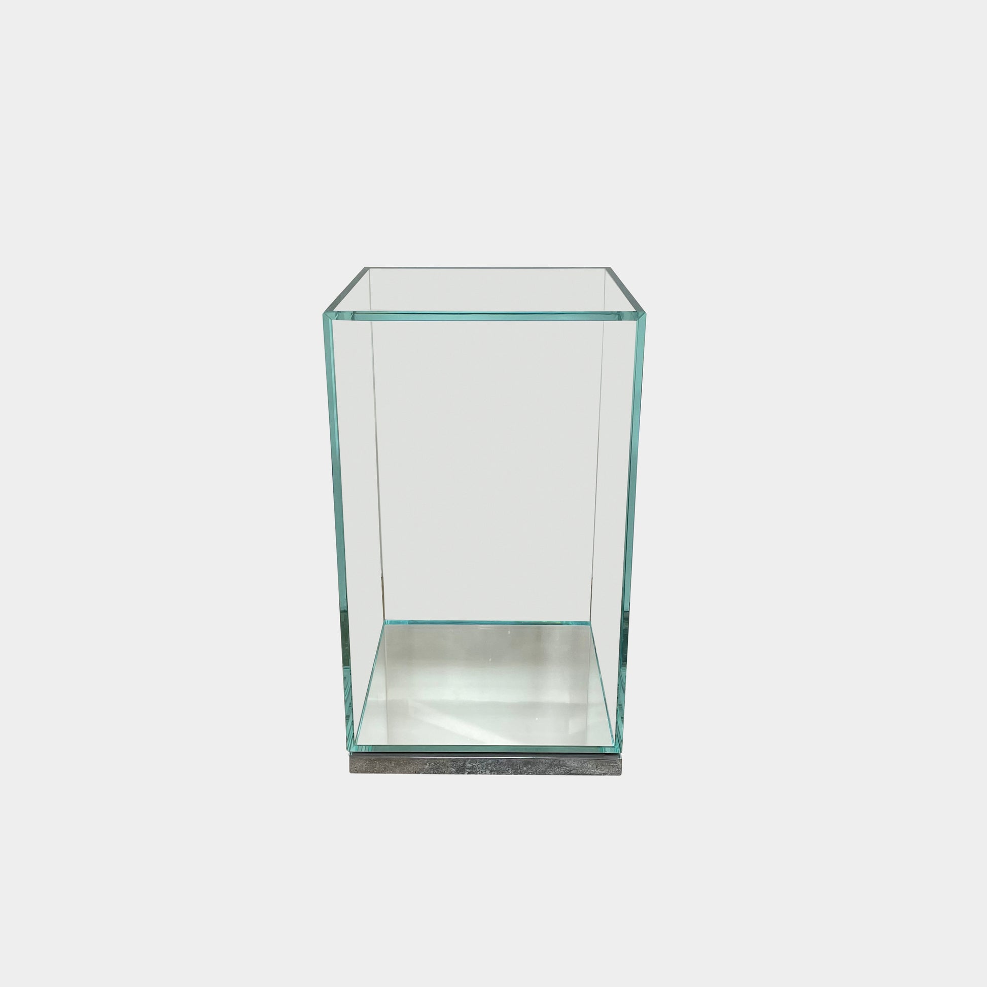 A clear rectangular glass display case with a metal base, inspired by the Cassina Volage side table Philippe Starck from Cassina, shown against a plain white background.