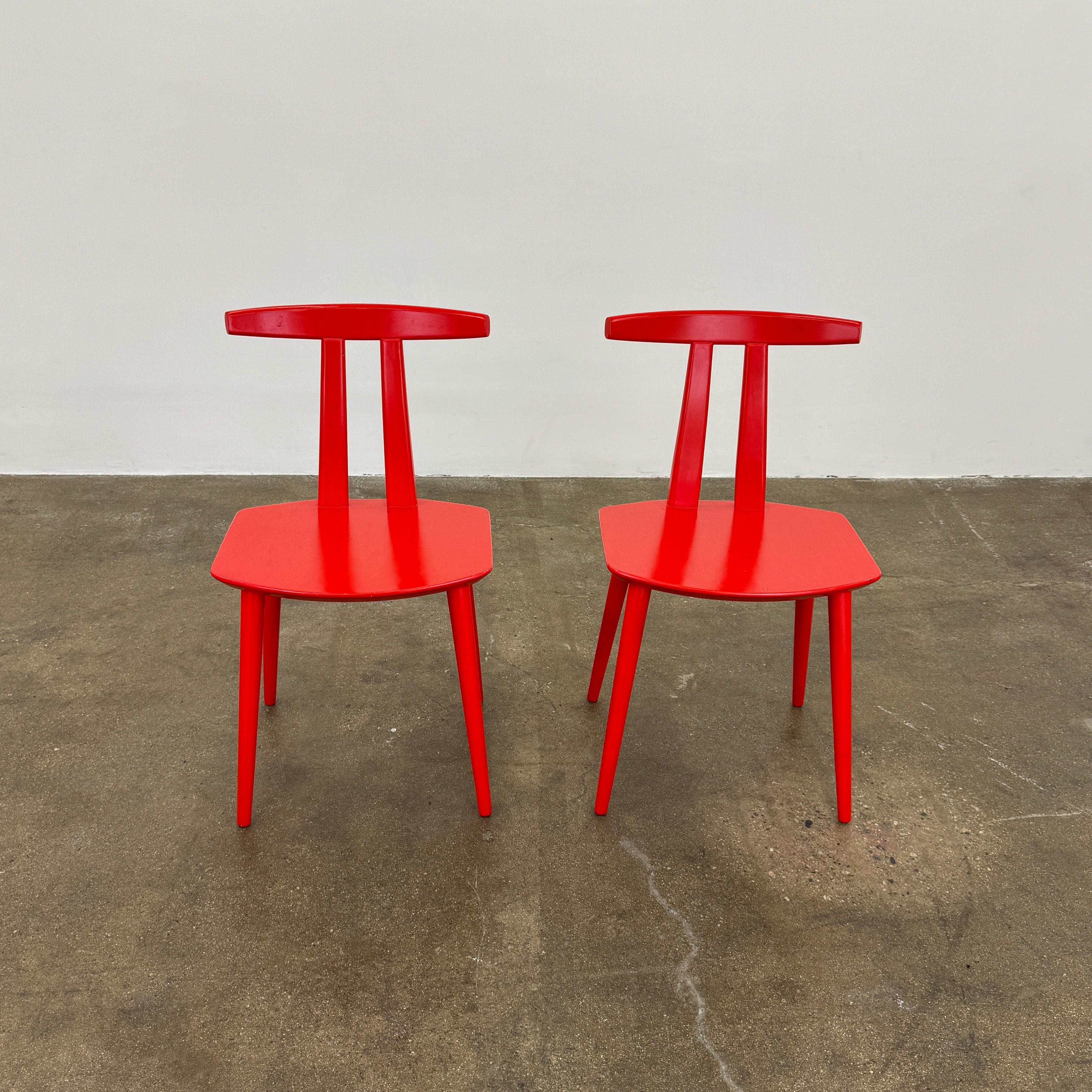 The Torii Chair by Bensen features a minimalist design with a round backrest and angled legs, crafted in red wood. Shown against a plain light background, this piece showcases Bensen's signature style.