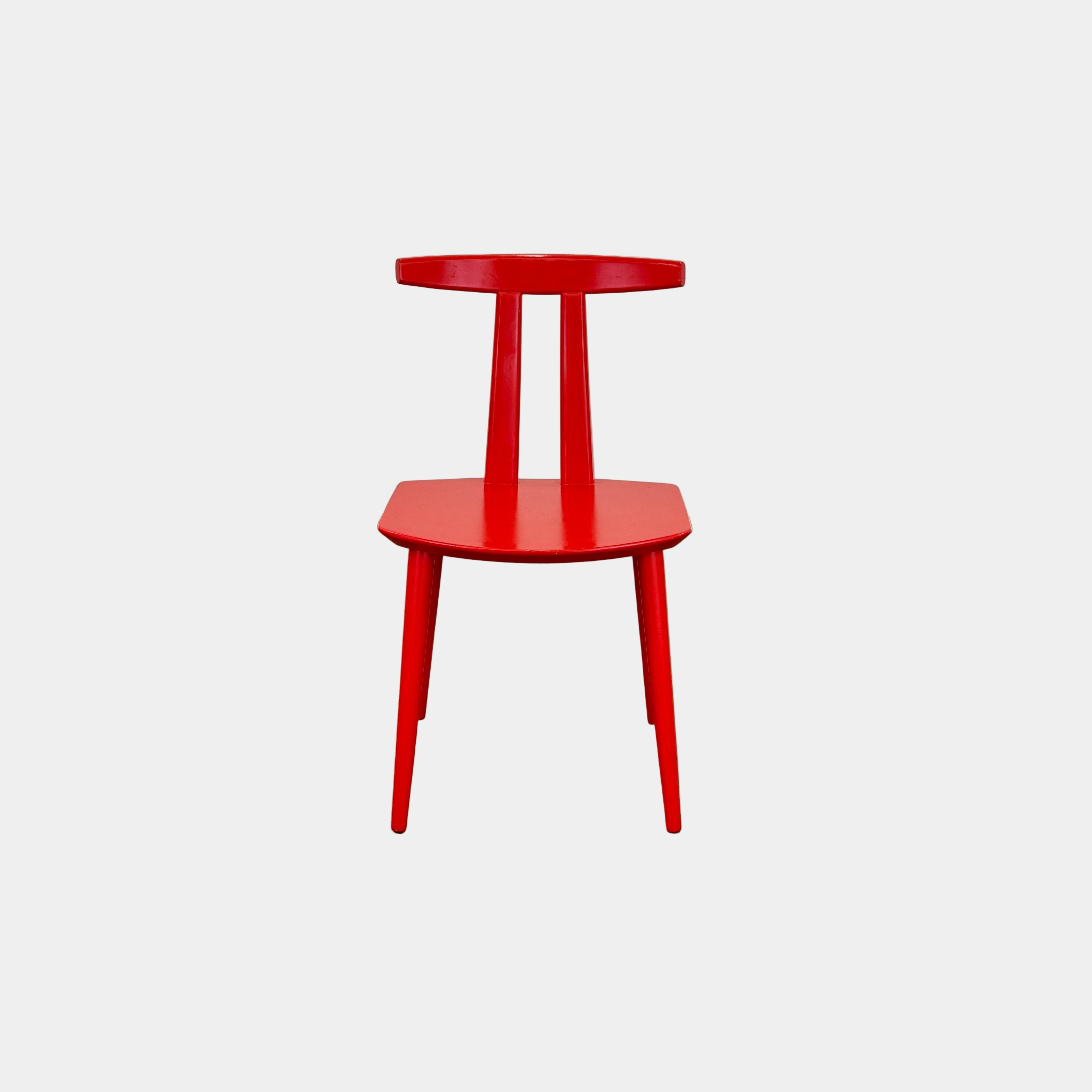 The Torii Chair by Bensen features a minimalist design with a round backrest and angled legs, crafted in red wood. Shown against a plain light background, this piece showcases Bensen's signature style.