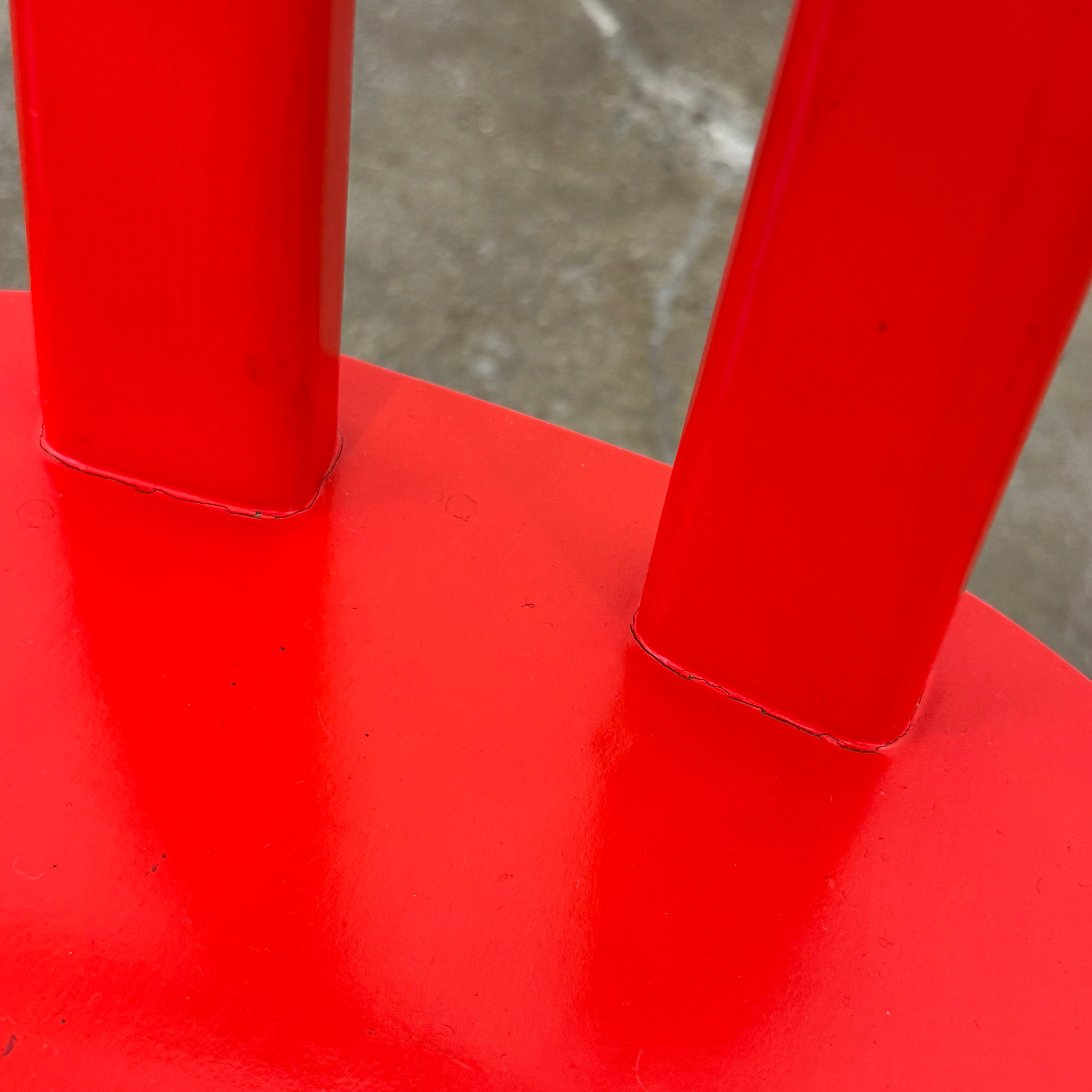 The Torii Chair by Bensen features a minimalist design with a round backrest and angled legs, crafted in red wood. Shown against a plain light background, this piece showcases Bensen's signature style.