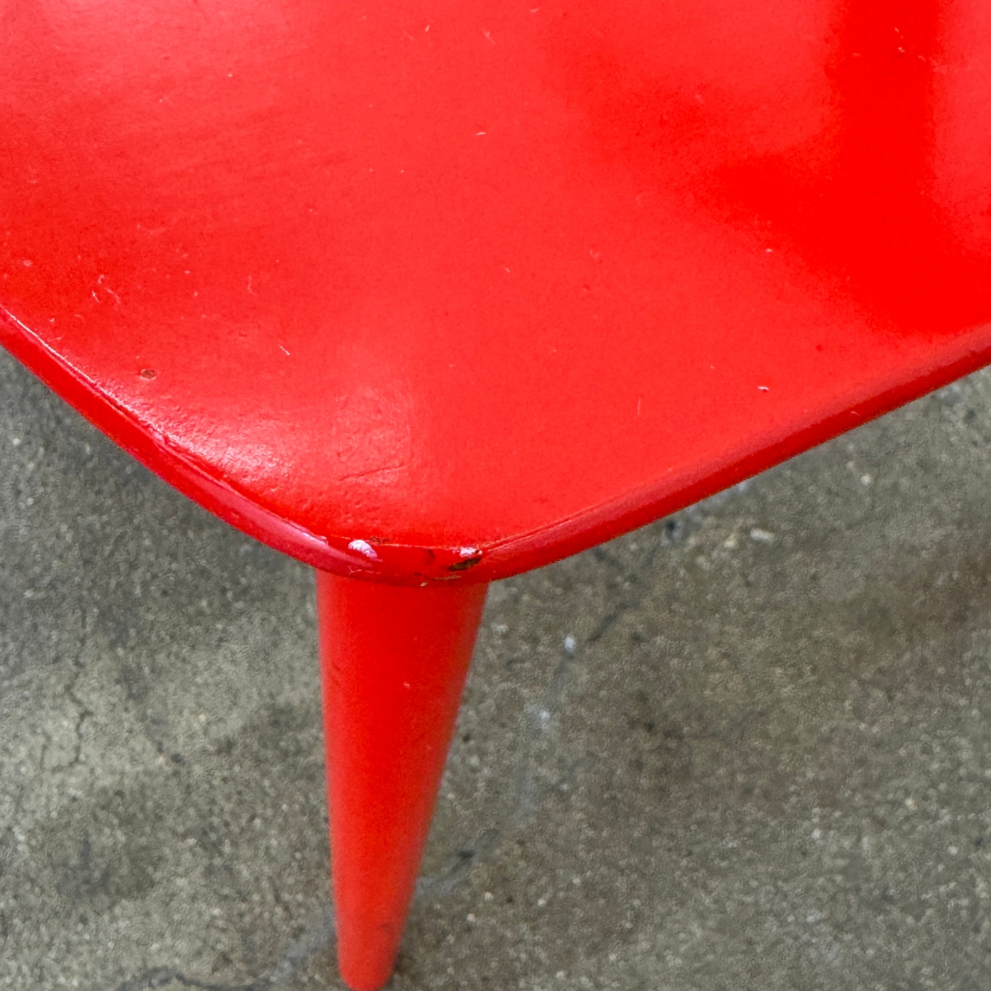 The Torii Chair by Bensen features a minimalist design with a round backrest and angled legs, crafted in red wood. Shown against a plain light background, this piece showcases Bensen's signature style.