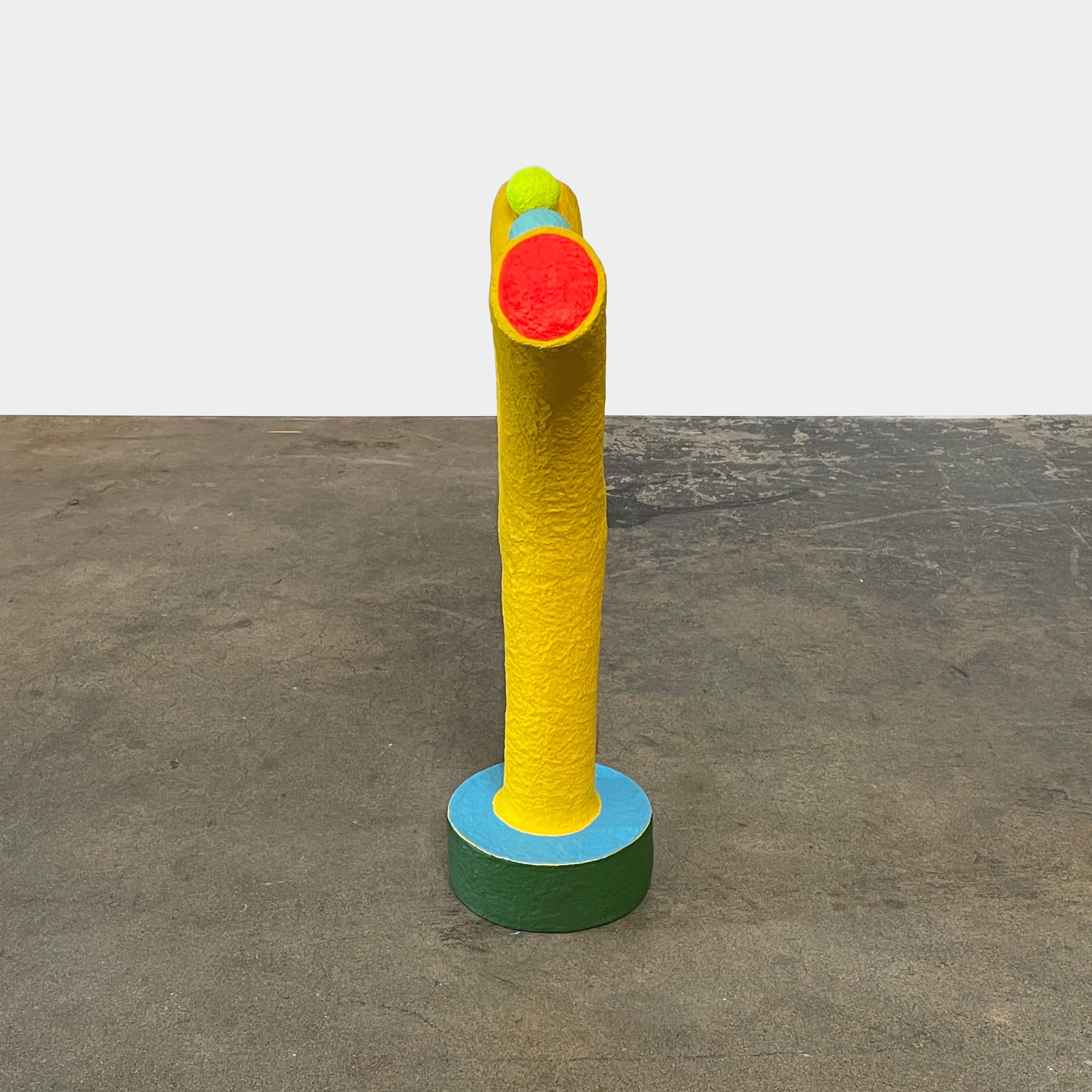 A yellow Gemel Sculpture No.99 with a blue ball in the middle created by Terri Chiao and Adam Frezza as part of their CHIAOZZA Gemel Sculpture series.