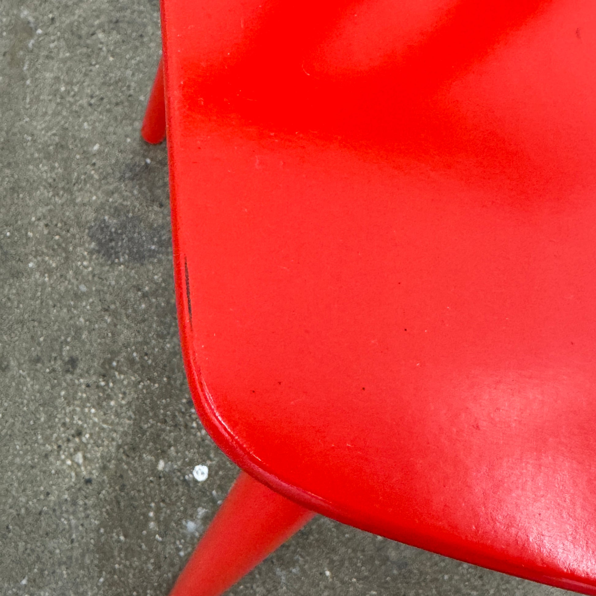 The Torii Chair by Bensen features a minimalist design with a round backrest and angled legs, crafted in red wood. Shown against a plain light background, this piece showcases Bensen's signature style.