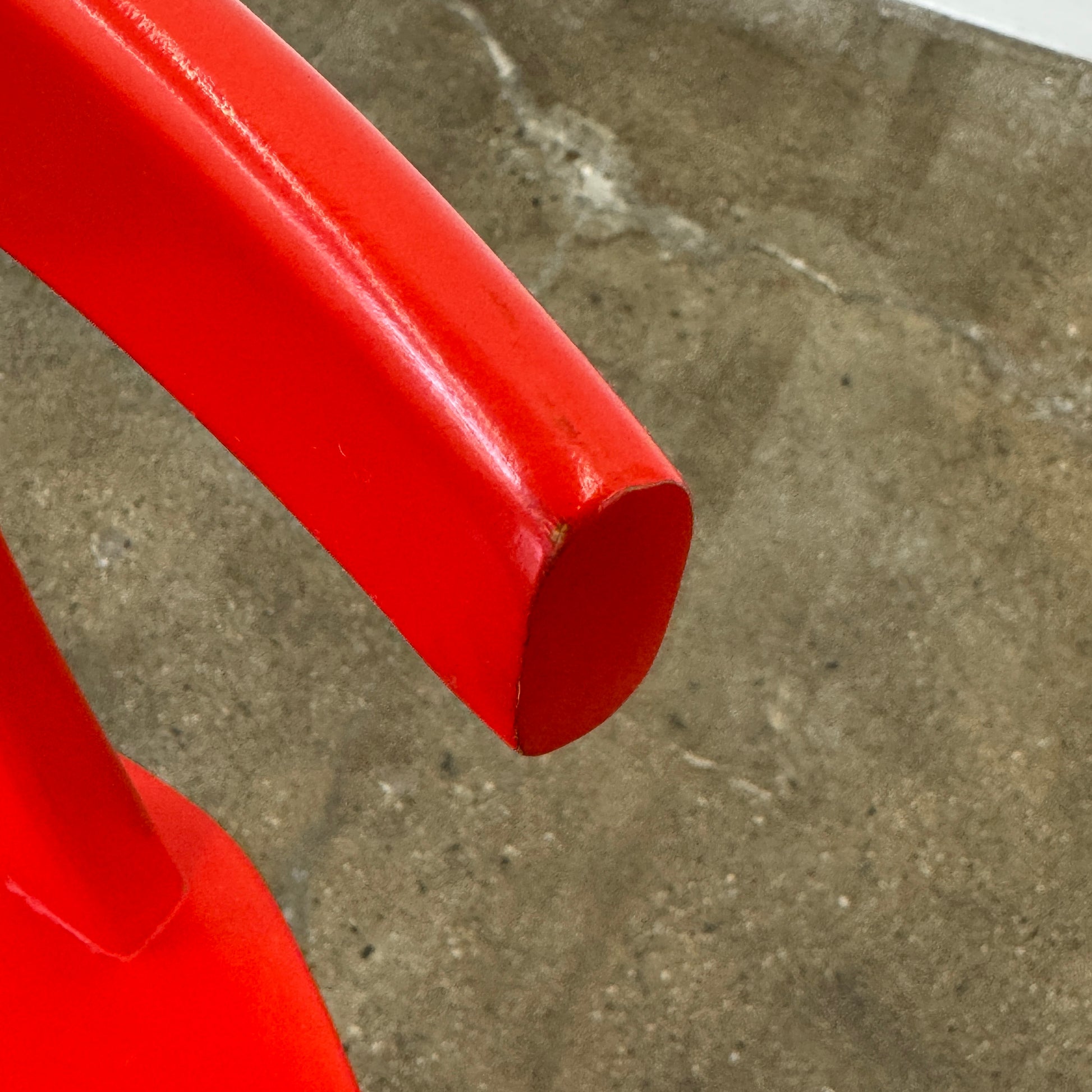 The Torii Chair by Bensen features a minimalist design with a round backrest and angled legs, crafted in red wood. Shown against a plain light background, this piece showcases Bensen's signature style.