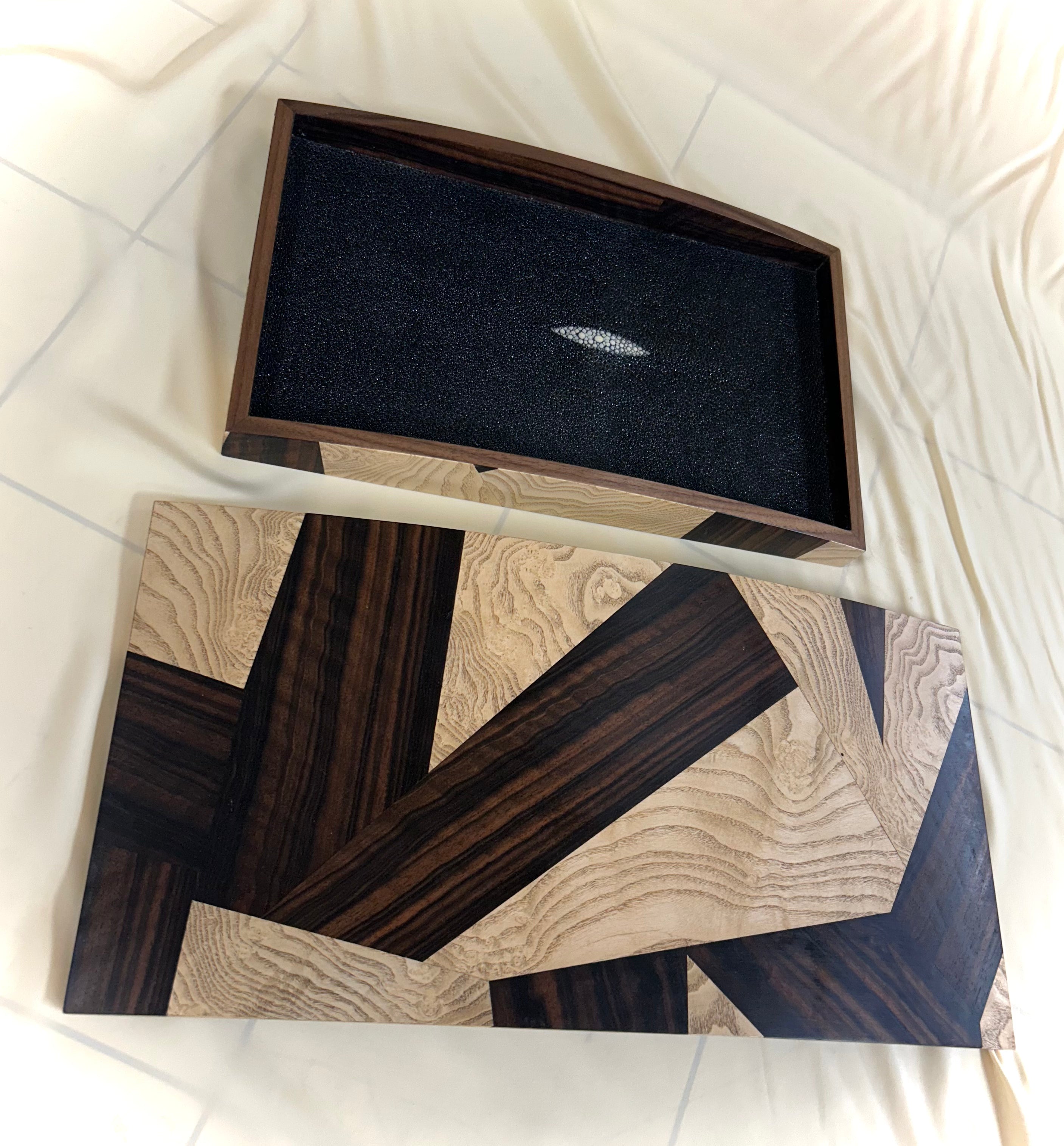 Rectangular storage box from Mike Fair Custom Furnishings, crafted with a curved top and showcasing a geometric zigzag pattern in Macassar ebony and ash burl, inspired by the artistic craftsmanship of Mike Fair.