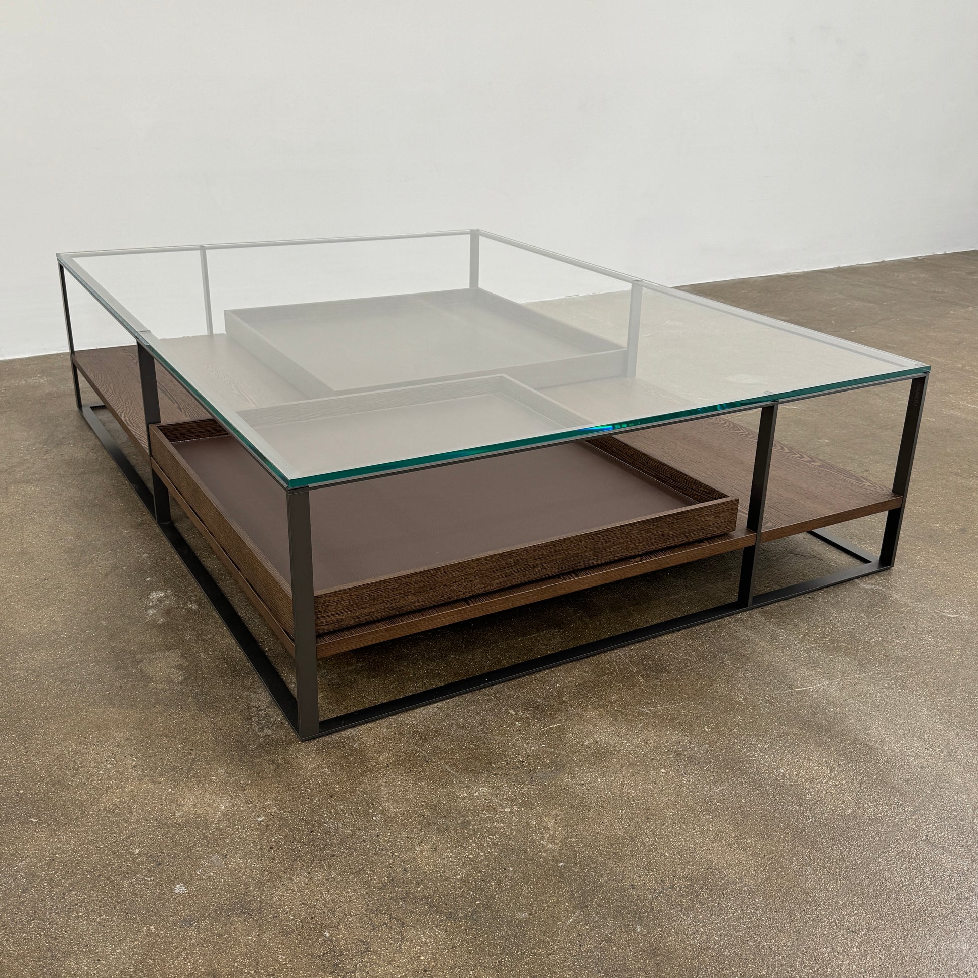 The Maxalto Lithos Coffee Table by Maxalto features a square metal frame, glass top, and two wooden lower shelves—one slightly raised—inspired by the original design. Shown against a plain white background.