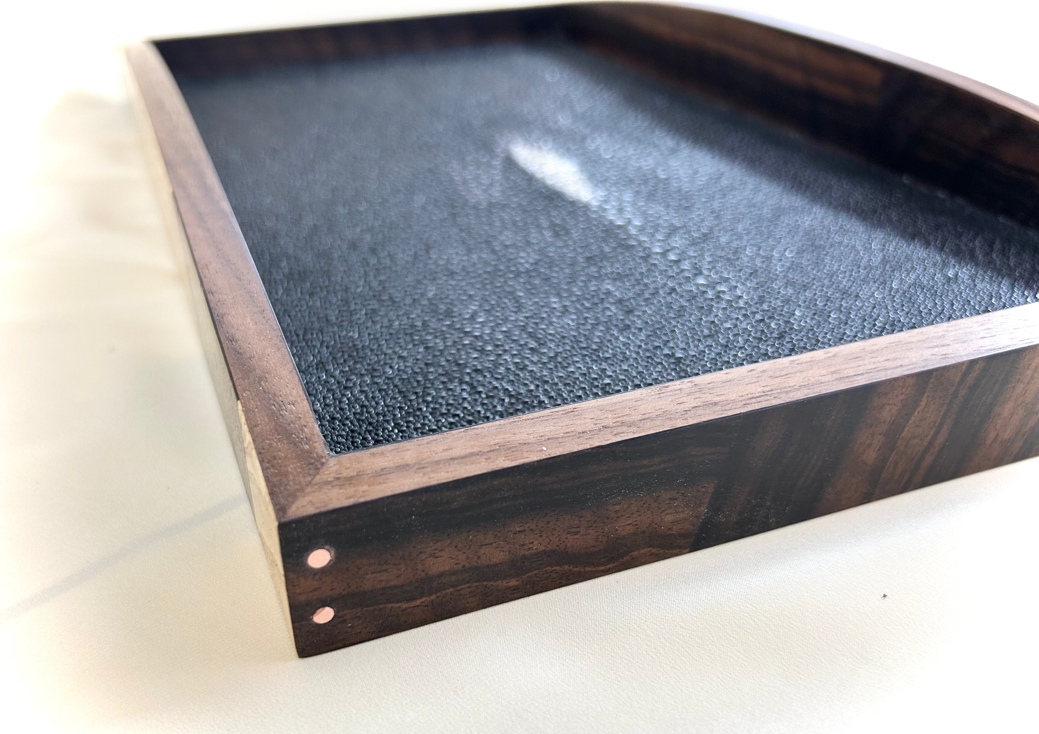 A rectangular table top storage box by Mike Fair Custom Furnishings, crafted from luxurious Macassar Ebony and Ash Burl with a geometric patterned lid, is displayed open to reveal a foam insert inside. The elegant Mike Fair Table Top Storage Box rests on a light fabric surface.