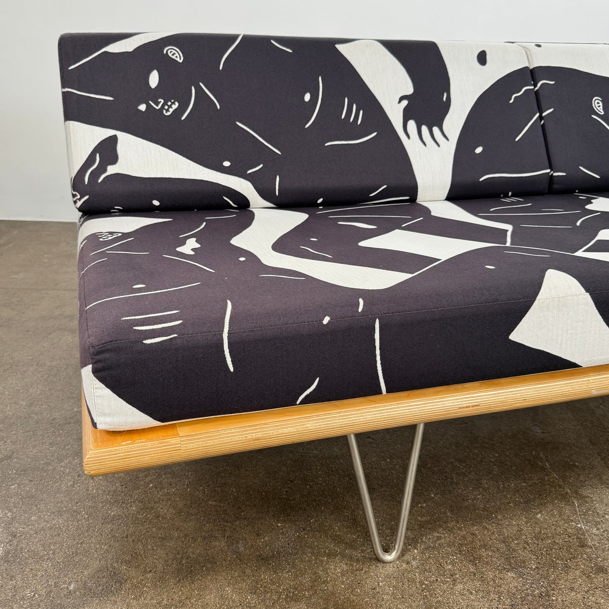 The Limited Edition Modernica + Cleon Peterson Case Study Daybed 2016 features metal hairpin legs and black-and-white cushions with abstract human figure illustrations by Cleon Peterson.