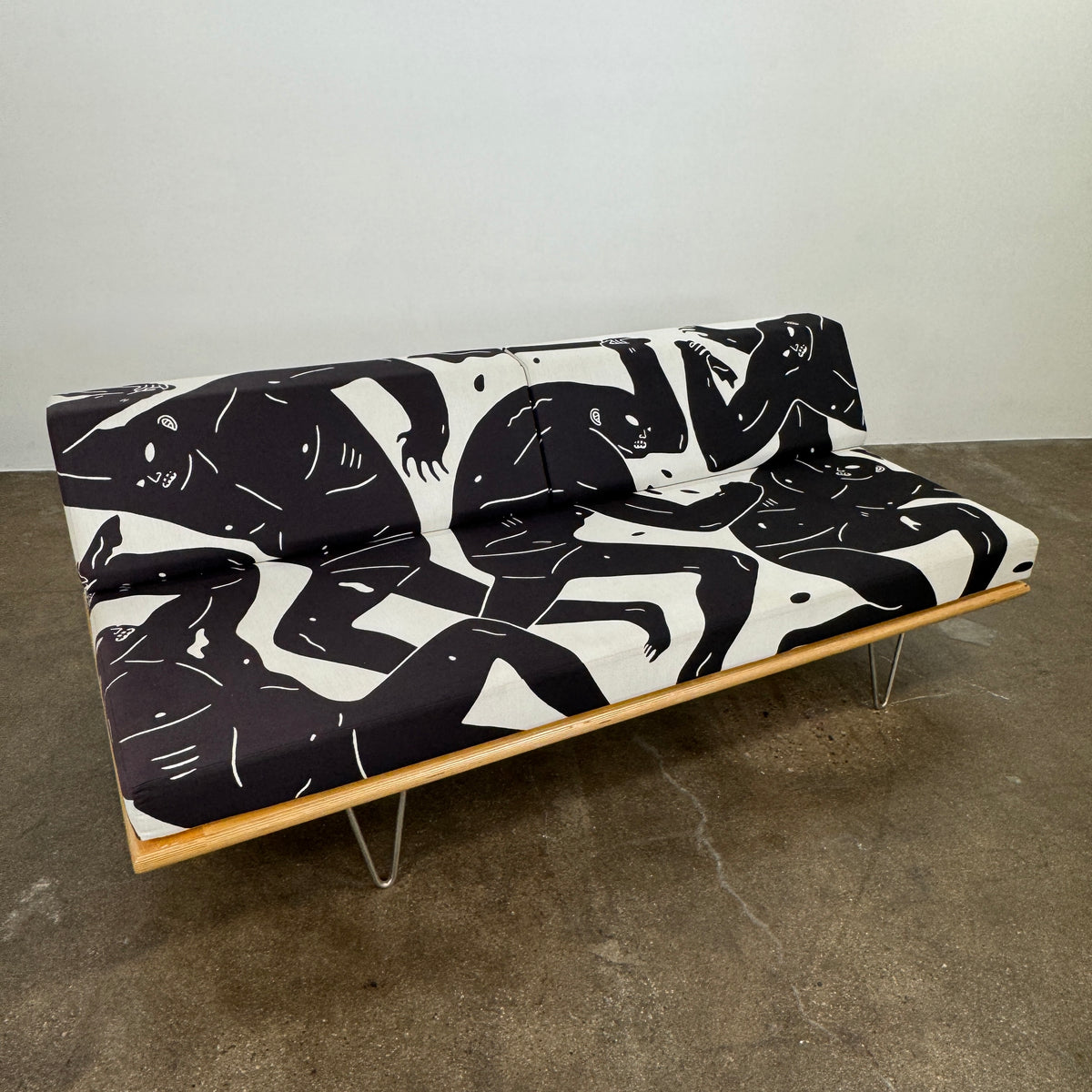 The Limited Edition Modernica + Cleon Peterson Case Study Daybed 2016 features metal hairpin legs and black-and-white cushions with abstract human figure illustrations by Cleon Peterson.