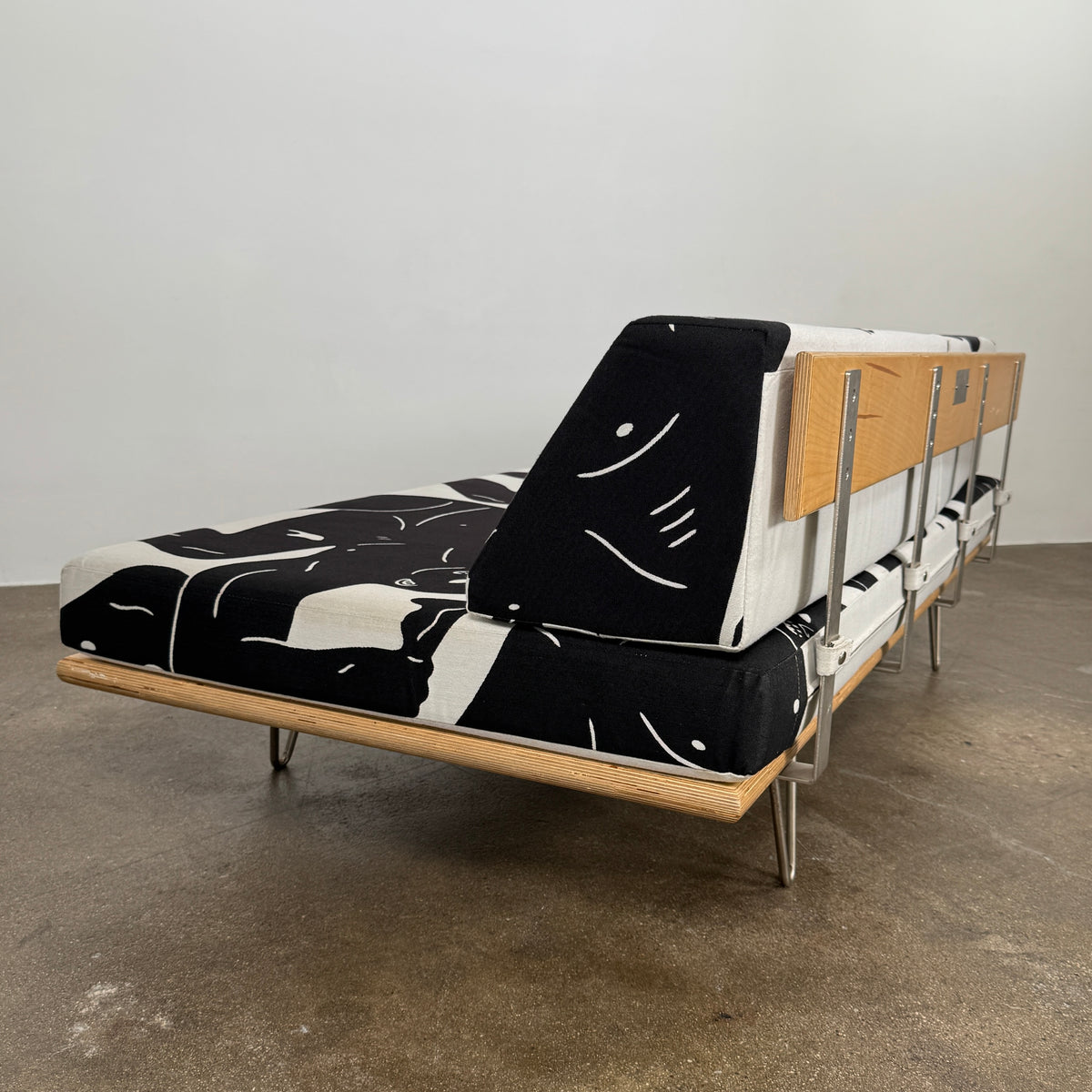 The Limited Edition Modernica + Cleon Peterson Case Study Daybed 2016 features metal hairpin legs and black-and-white cushions with abstract human figure illustrations by Cleon Peterson.