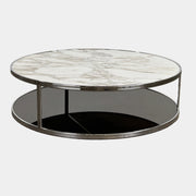 The Minotti Huber Coffee Table by Minotti features a round design with a white statuary marble top, dark lower shelf, and sleek metal frame, set against a plain light background.