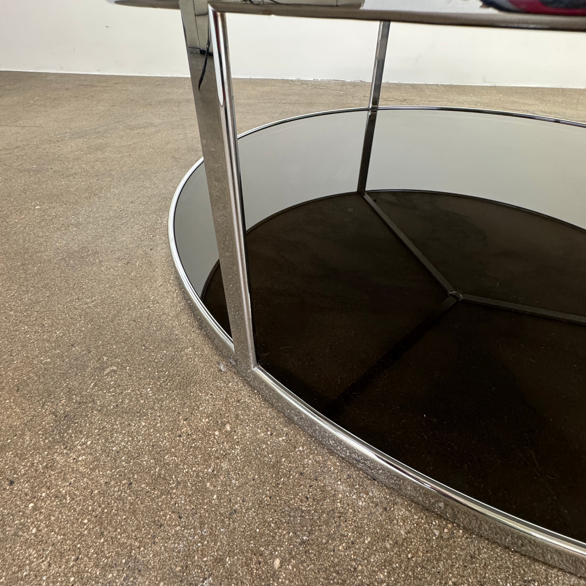 The Minotti Huber Coffee Table by Minotti features a round design with a white statuary marble top, dark lower shelf, and sleek metal frame, set against a plain light background.