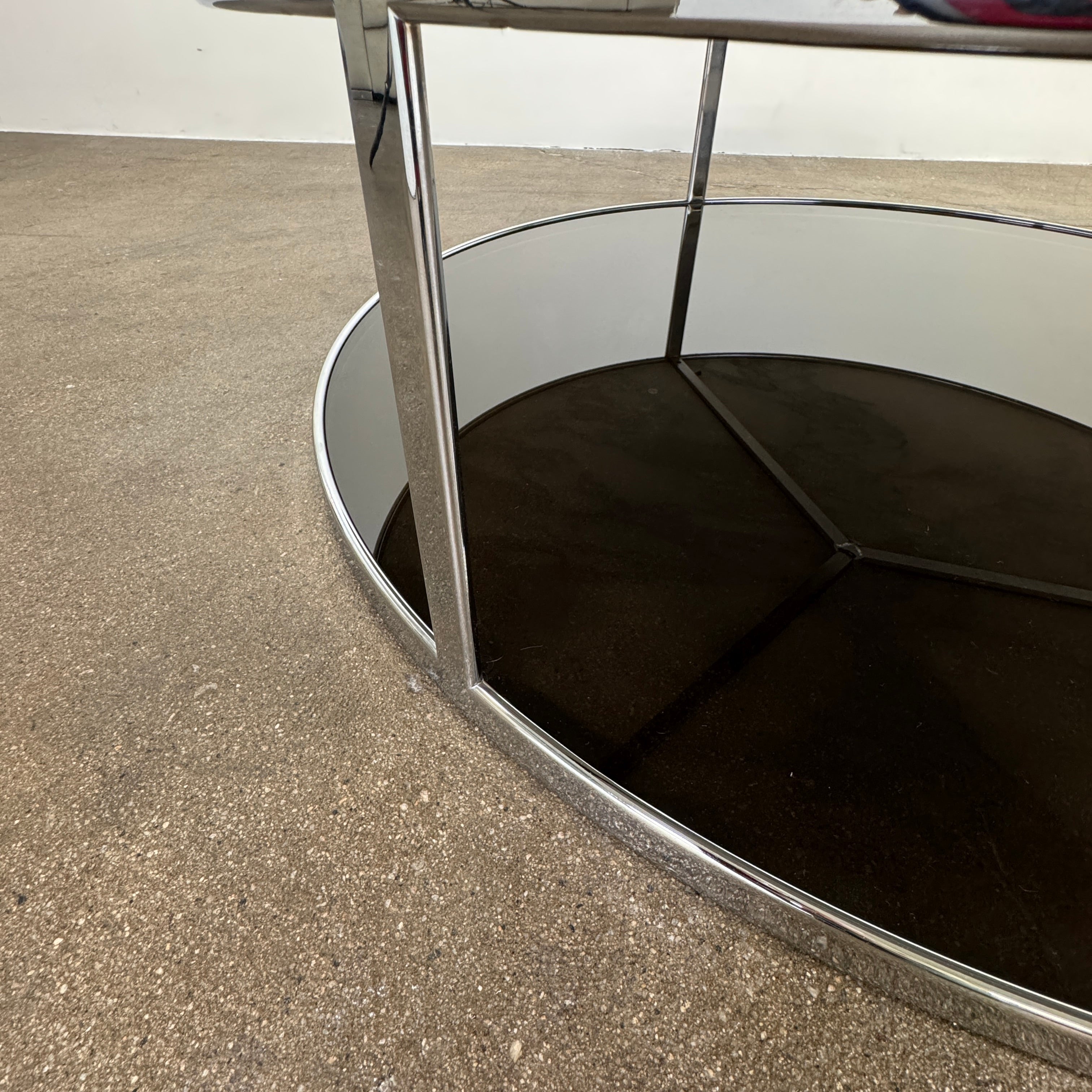 The Minotti Huber Coffee Table by Minotti features a round design with a white statuary marble top, dark lower shelf, and sleek metal frame, set against a plain light background.