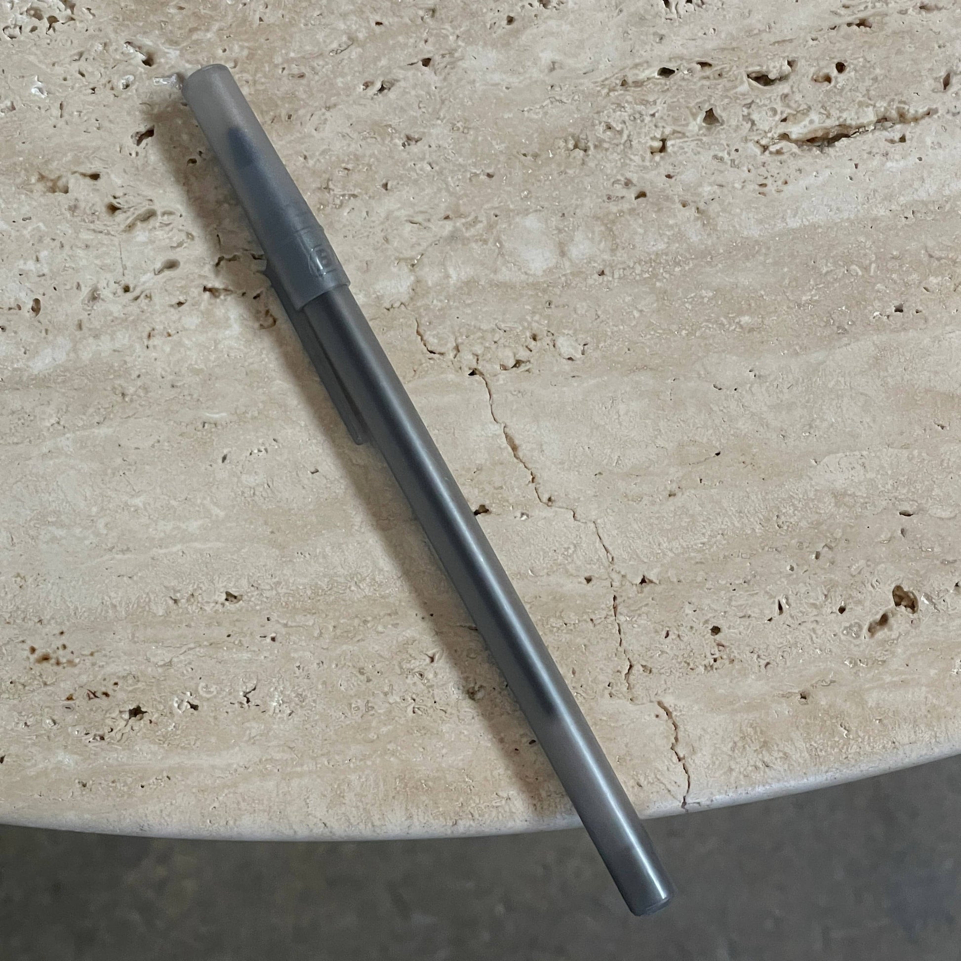 A Delcourt Collection Ouk Sylver Travertine Table, handcrafted and imported from France, is displayed on a white background.