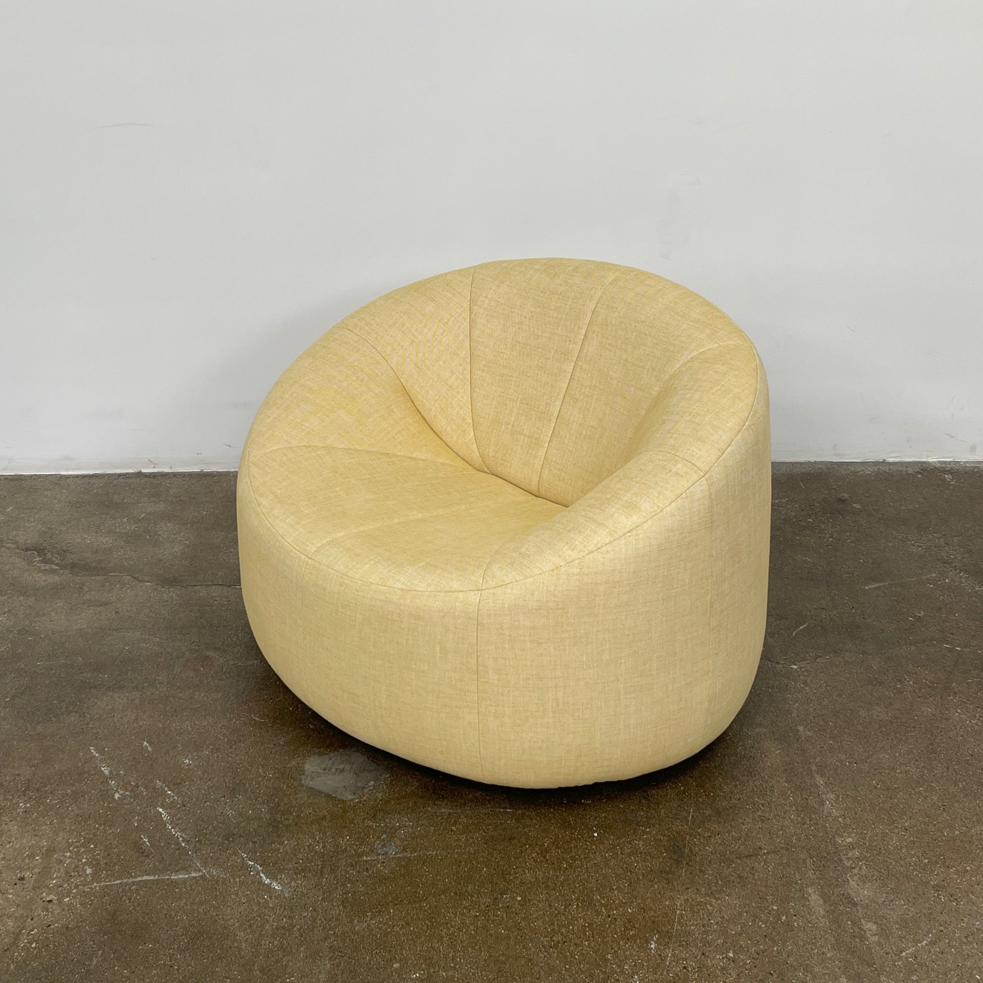 A light yellow Ligne Roset Pumpkin Swivel Lounge Chair with a round shape, low back, and wide seat is shown against a plain white background.