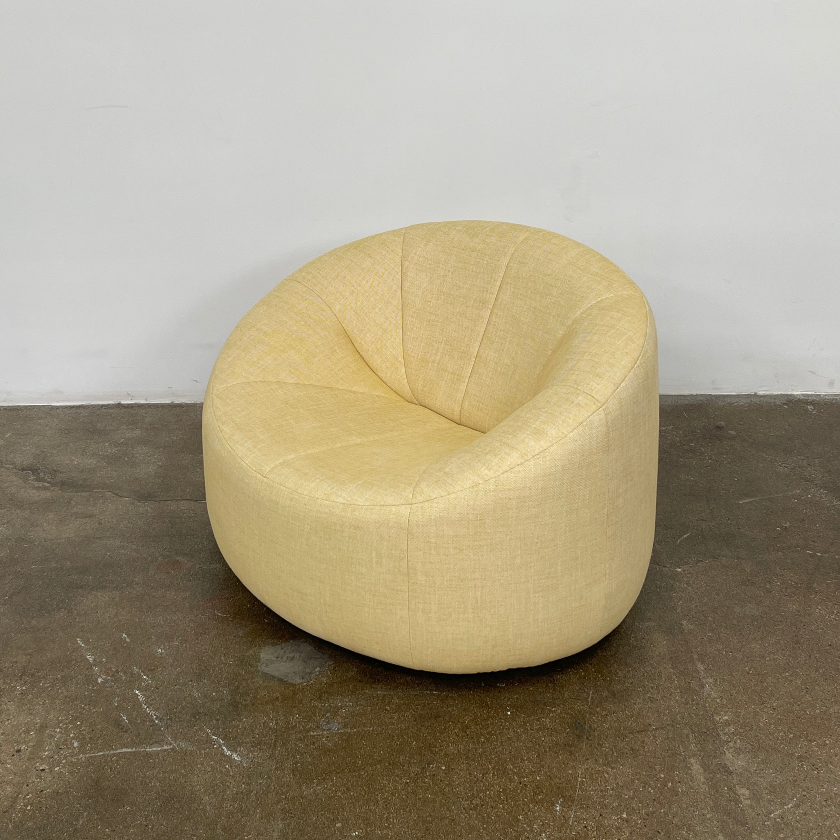 A light yellow Ligne Roset Pumpkin Swivel Lounge Chair with a round shape, low back, and wide seat is shown against a plain white background.