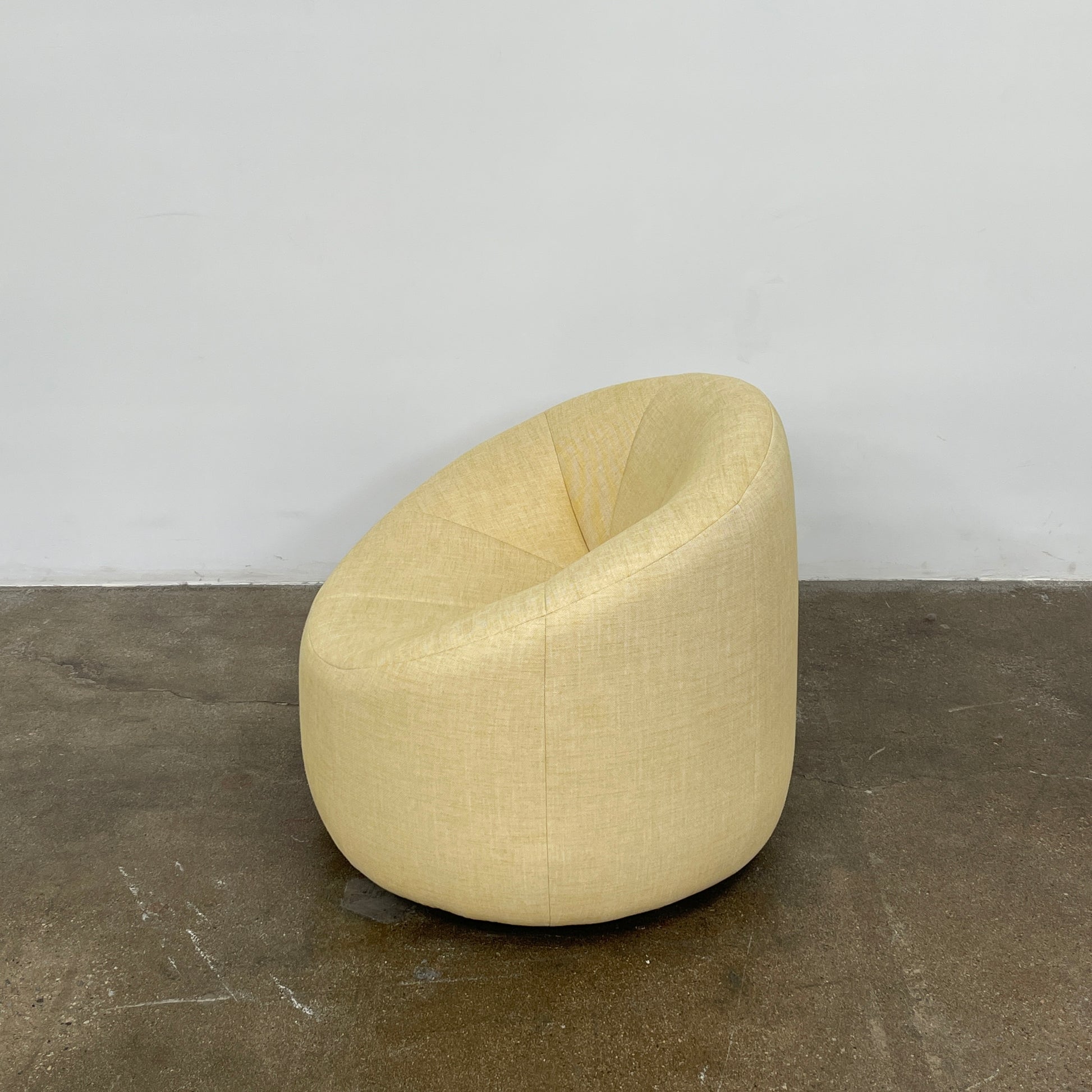 A light yellow Ligne Roset Pumpkin Swivel Lounge Chair with a round shape, low back, and wide seat is shown against a plain white background.
