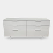The Modern Resale Ligne Roset Everywhere 6 Drawer Dresser is a white, minimalist piece with sleek metal handles and two sturdy metal legs, elegantly presented in front of a plain white background.