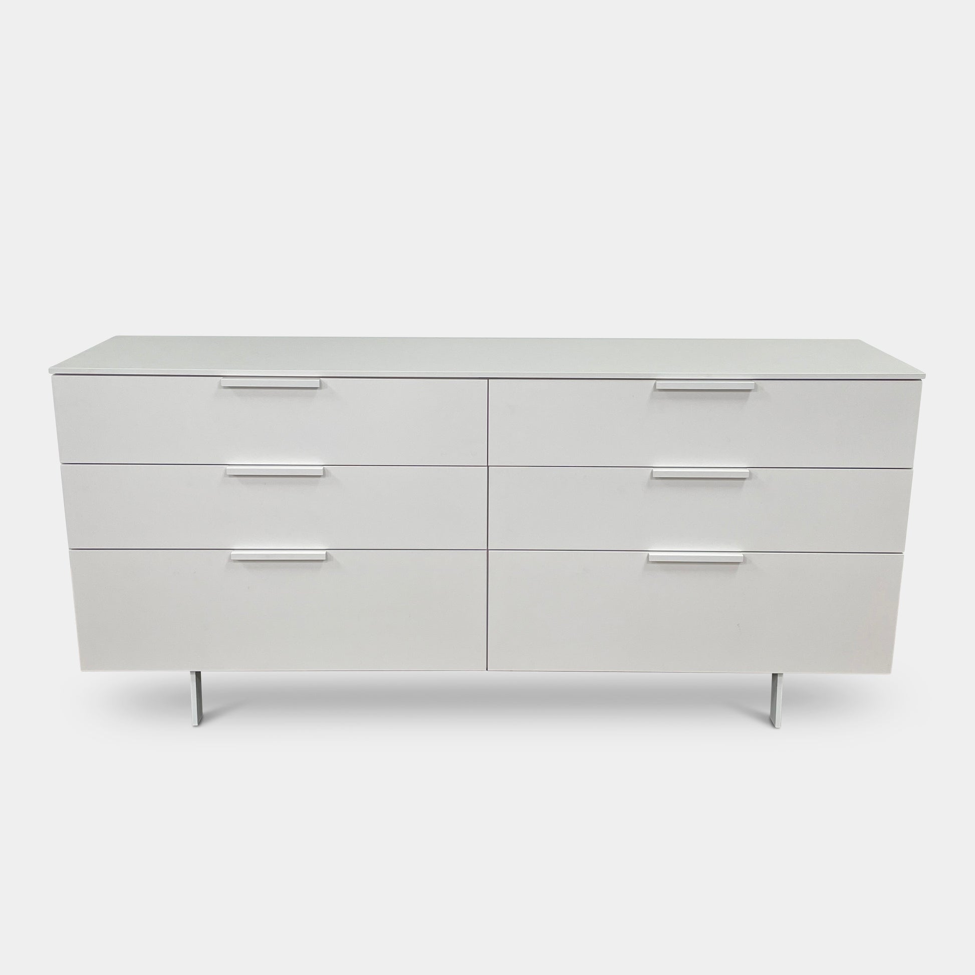 The Modern Resale Ligne Roset Everywhere 6 Drawer Dresser is a white, minimalist piece with sleek metal handles and two sturdy metal legs, elegantly presented in front of a plain white background.