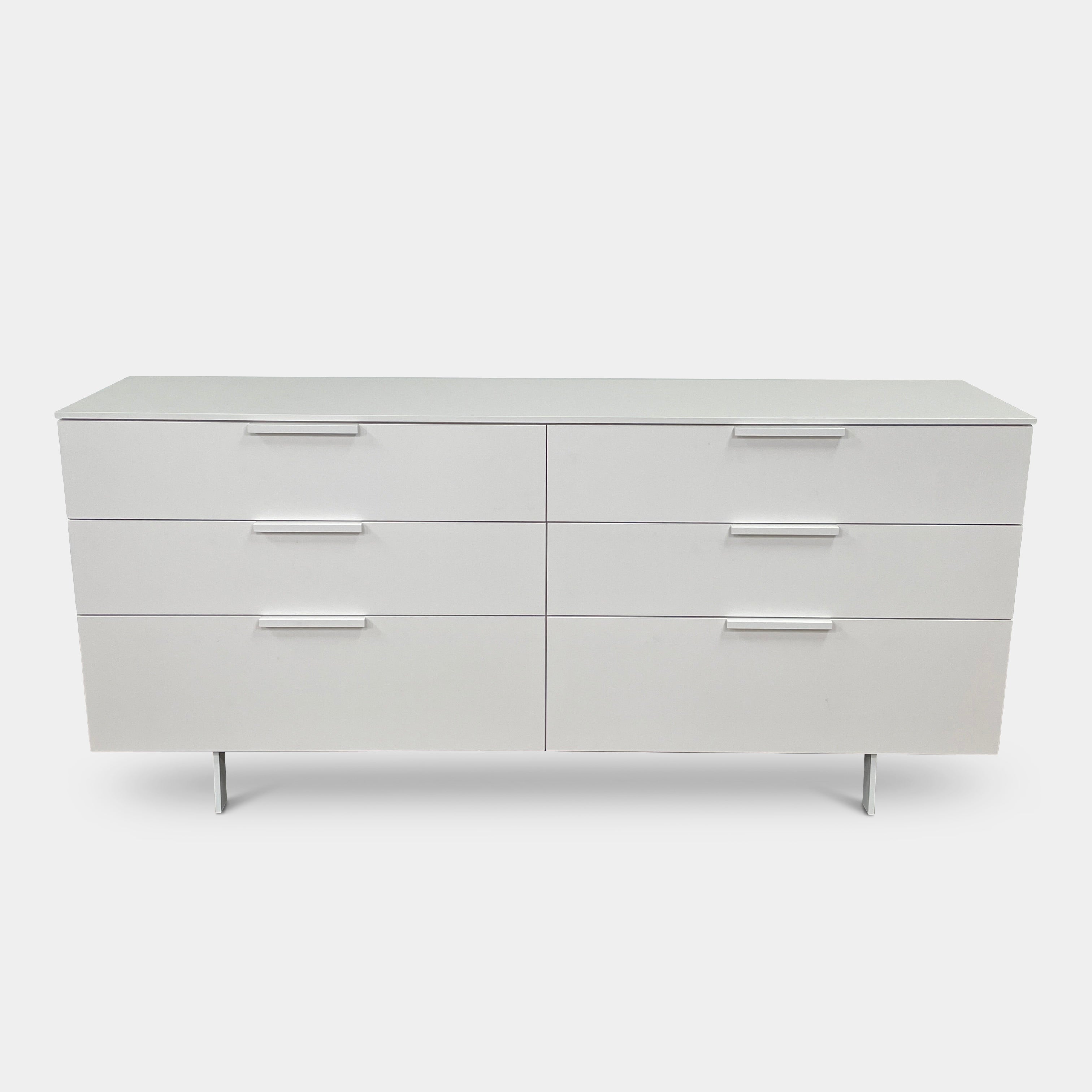 The Modern Resale Ligne Roset Everywhere 6 Drawer Dresser is a white, minimalist piece with sleek metal handles and two sturdy metal legs, elegantly presented in front of a plain white background.