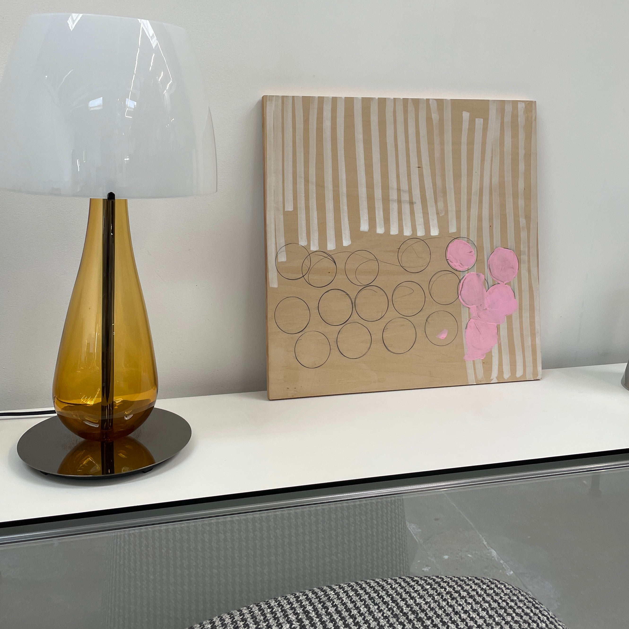 The experimental art piece "Switch" by Allison Caesar showcases vertical white lines, circular outlines, and pink patches on a wooden background.