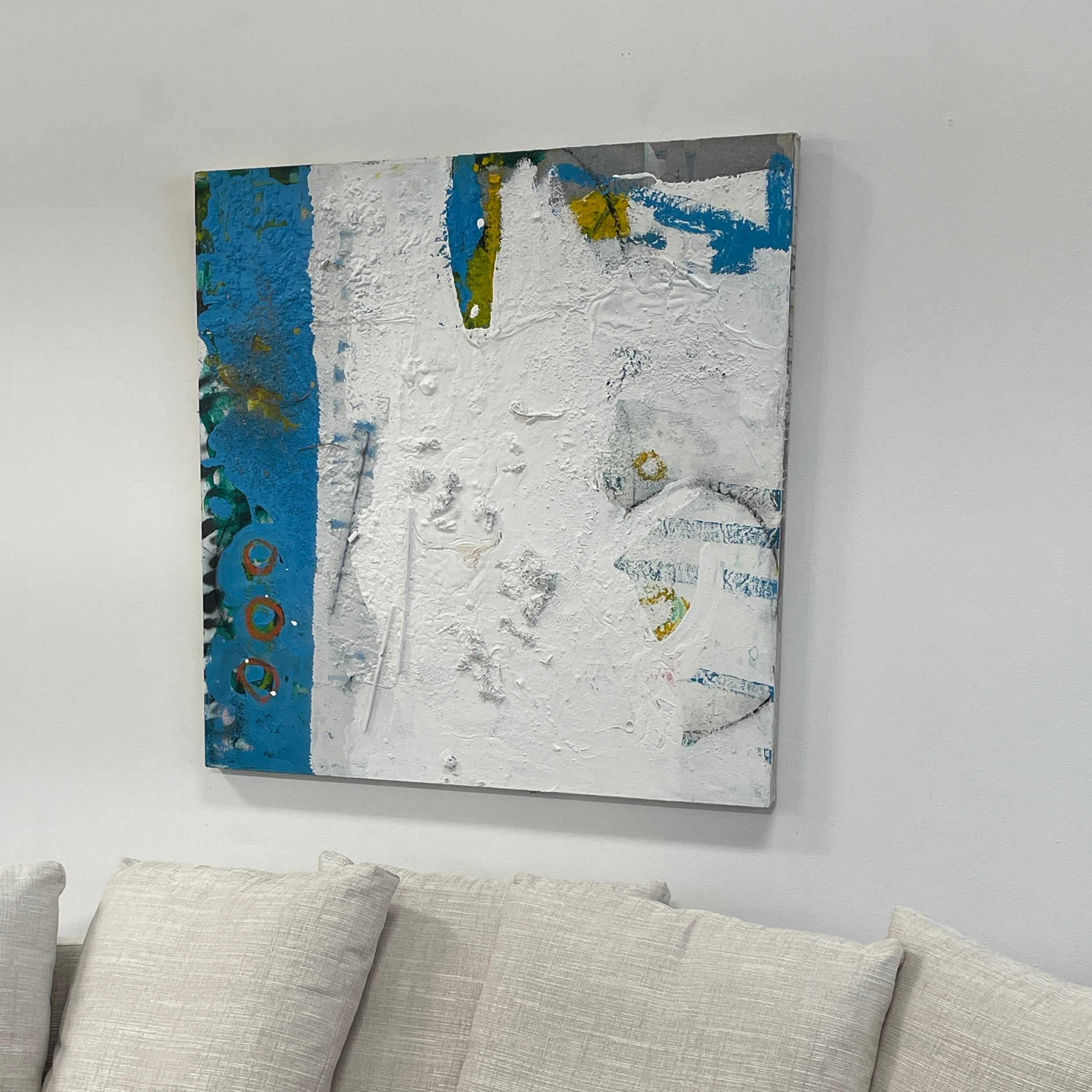 Artist's 'Painting: Variation' by Allison Caesar showcases textured layers of white, blue, with subtle yellow and green. Circular patterns on the left blend collage elements, mixing paint with relief details.