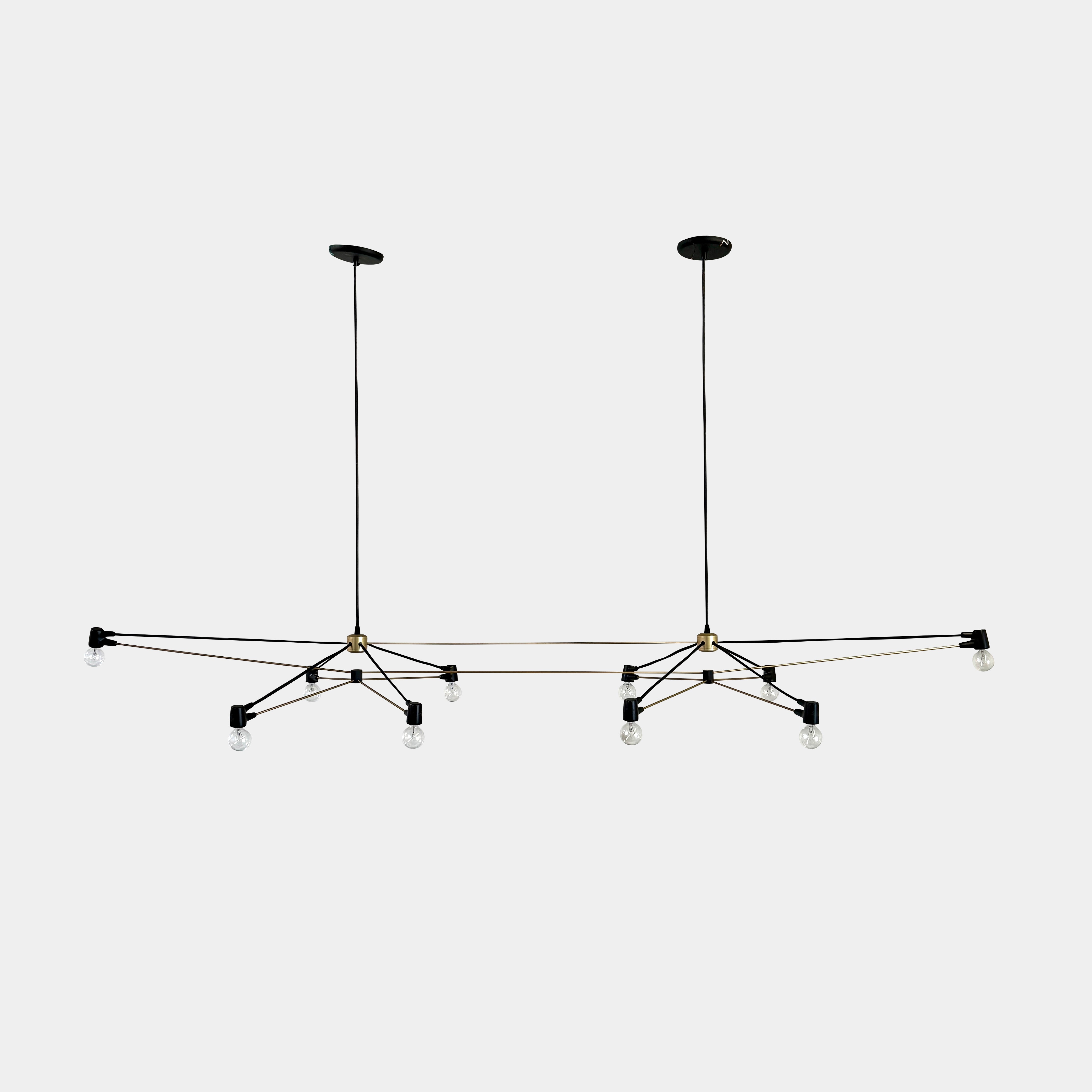 Two Ravenhill Studio Double Church Chandeliers by Ravenhill Studio, featuring exposed bulbs and modern black metal design, hang from a white industrial ceiling with visible beams, creating striking entryway lighting.