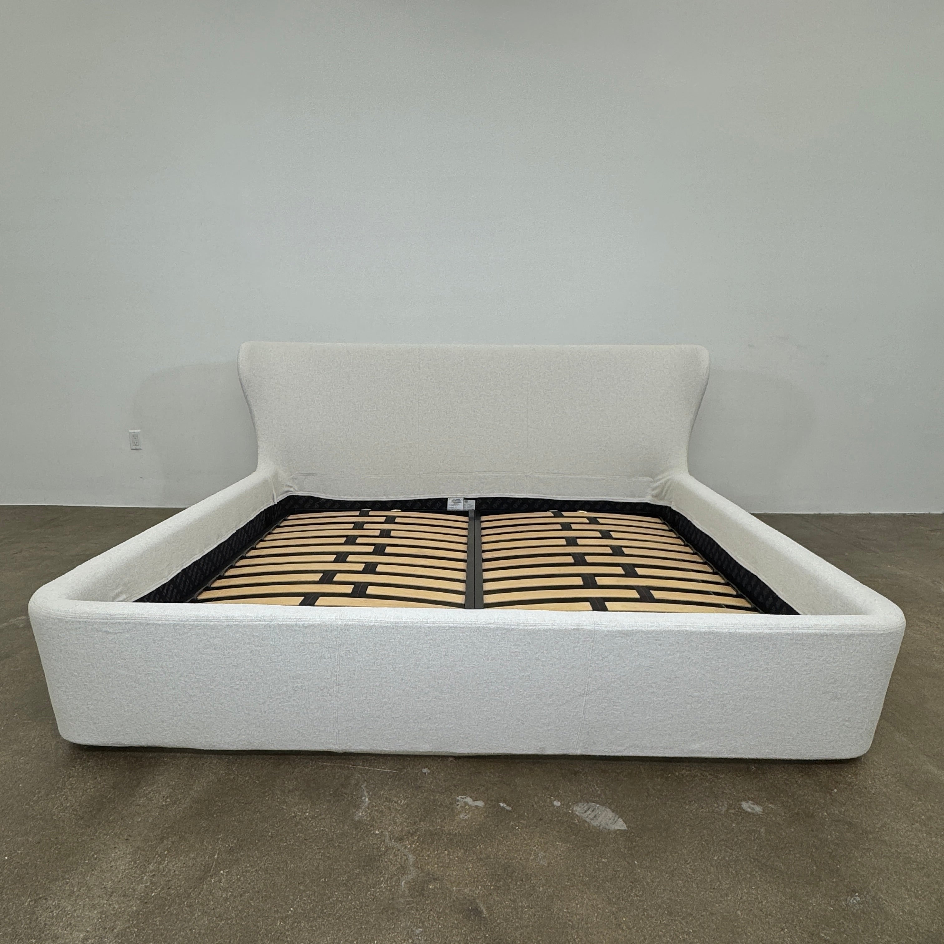 The B&B Italia Papilio King Bed by B&B Italia features a modern upholstered frame, cushioned headboard, and exposed wooden slats—ideal for contemporary bedrooms. Shown on a white background.