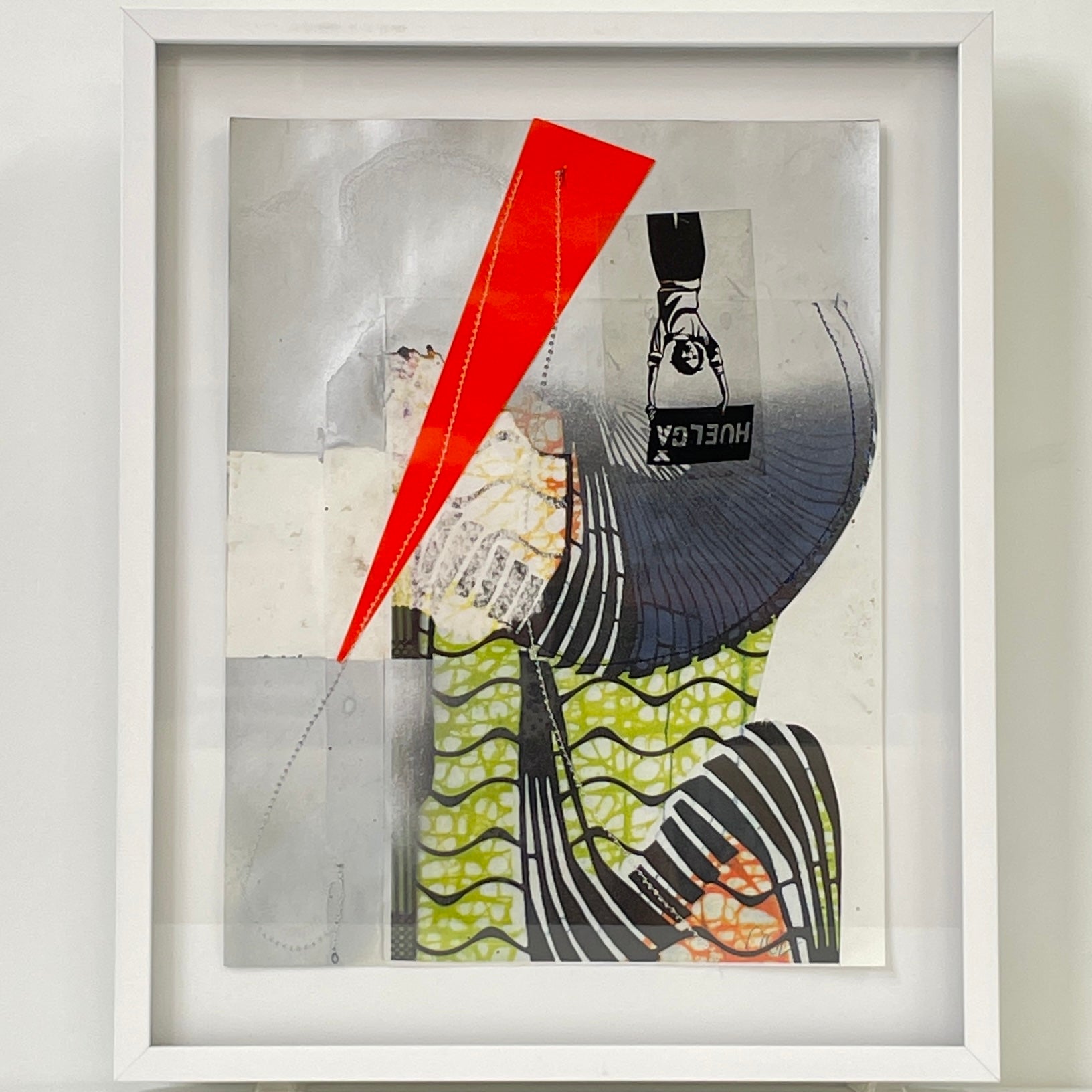The Allison Caesar Mixed Media Framed Collage Number 6 by Modern Resale features abstract geometric lines, wavy green patterns, a striking red triangle, and a partial sneaker image with "HUGER" text—all displayed in a crisp white frame.