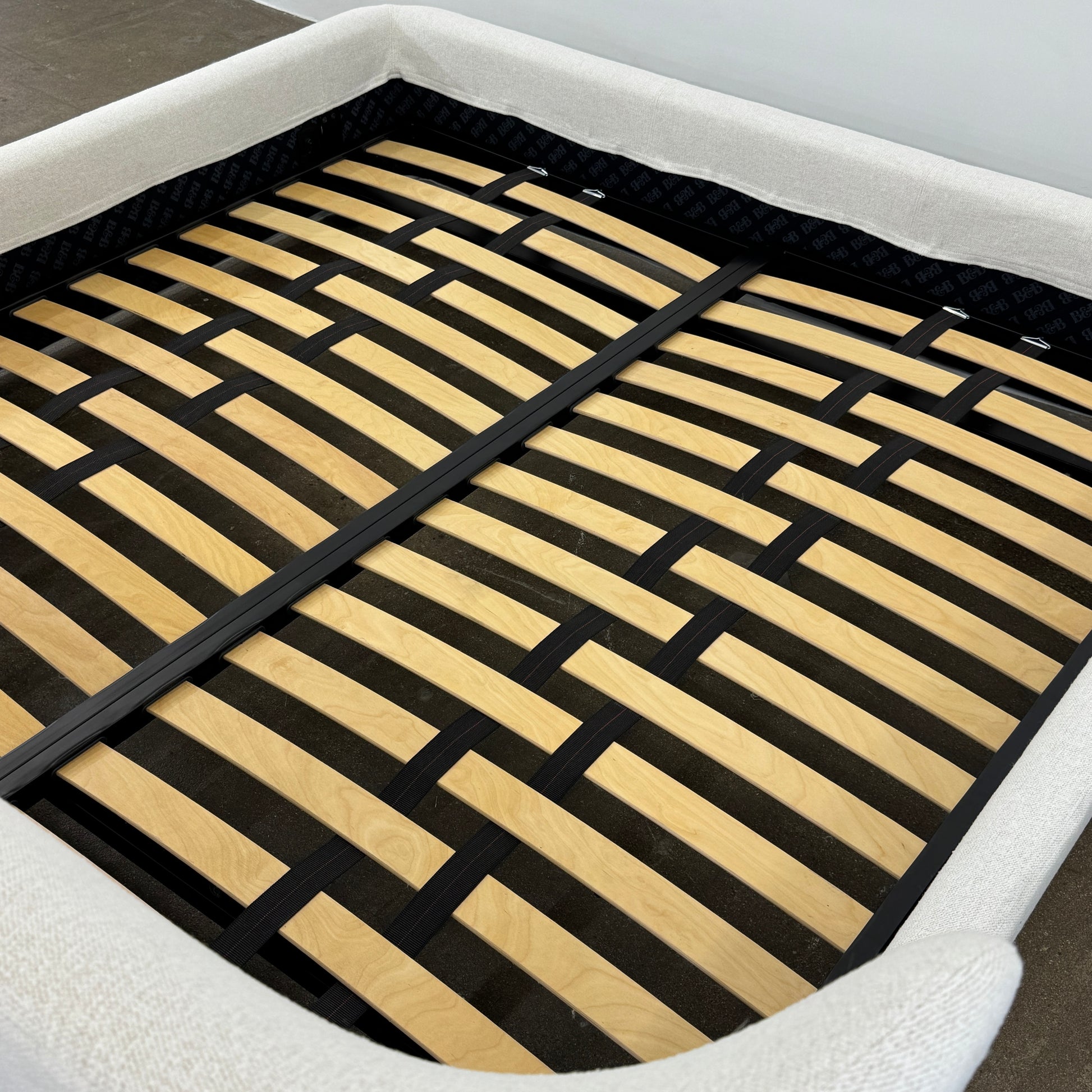 The B&B Italia Papilio King Bed by B&B Italia features a modern upholstered frame, cushioned headboard, and exposed wooden slats—ideal for contemporary bedrooms. Shown on a white background.