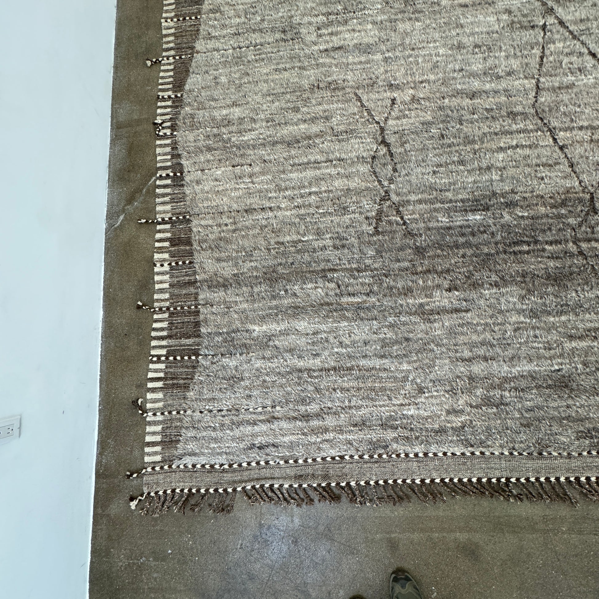 The Mehraban Gilavar Rug (13' x 15'.5") by Mehraban features handwoven, textured neutral tones, fringe tassels on the edges, and striped and patterned designs.
