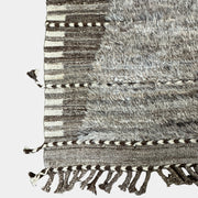 The Mehraban Gilavar Rug (13' x 15'.5") by Mehraban features handwoven, textured neutral tones, fringe tassels on the edges, and striped and patterned designs.