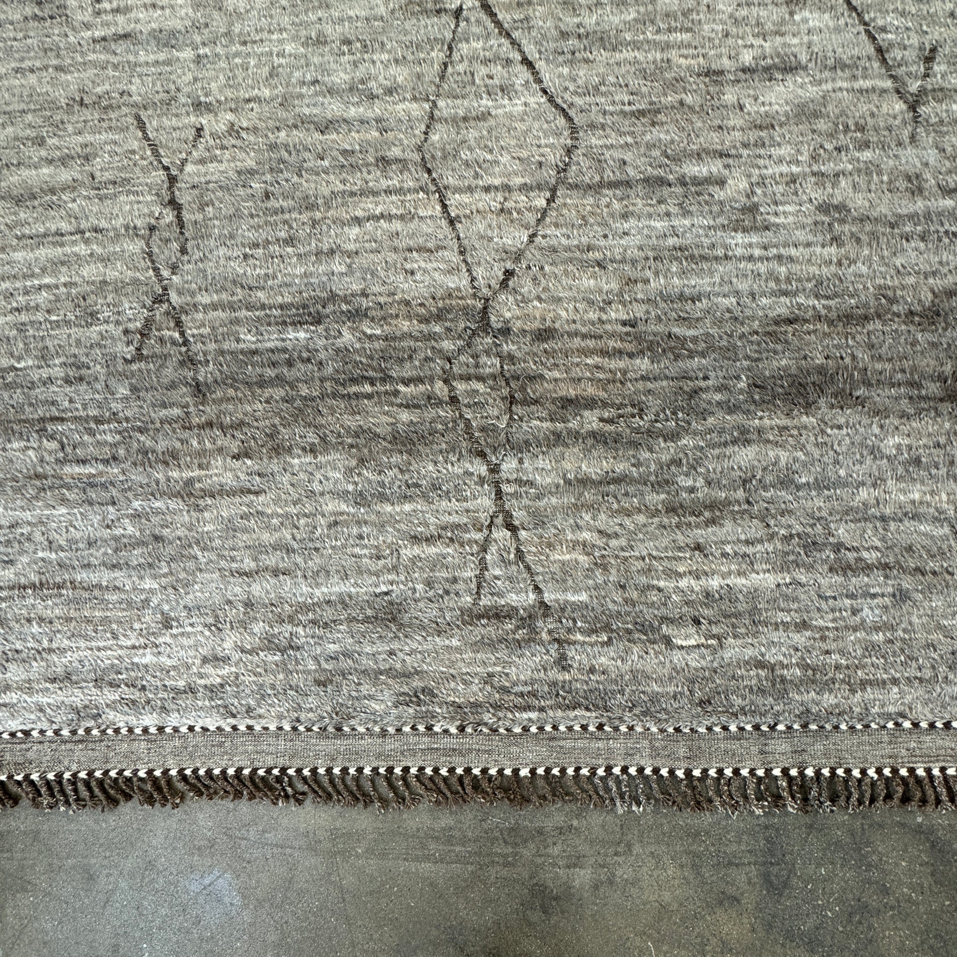 The Mehraban Gilavar Rug (13' x 15'.5") by Mehraban features handwoven, textured neutral tones, fringe tassels on the edges, and striped and patterned designs.