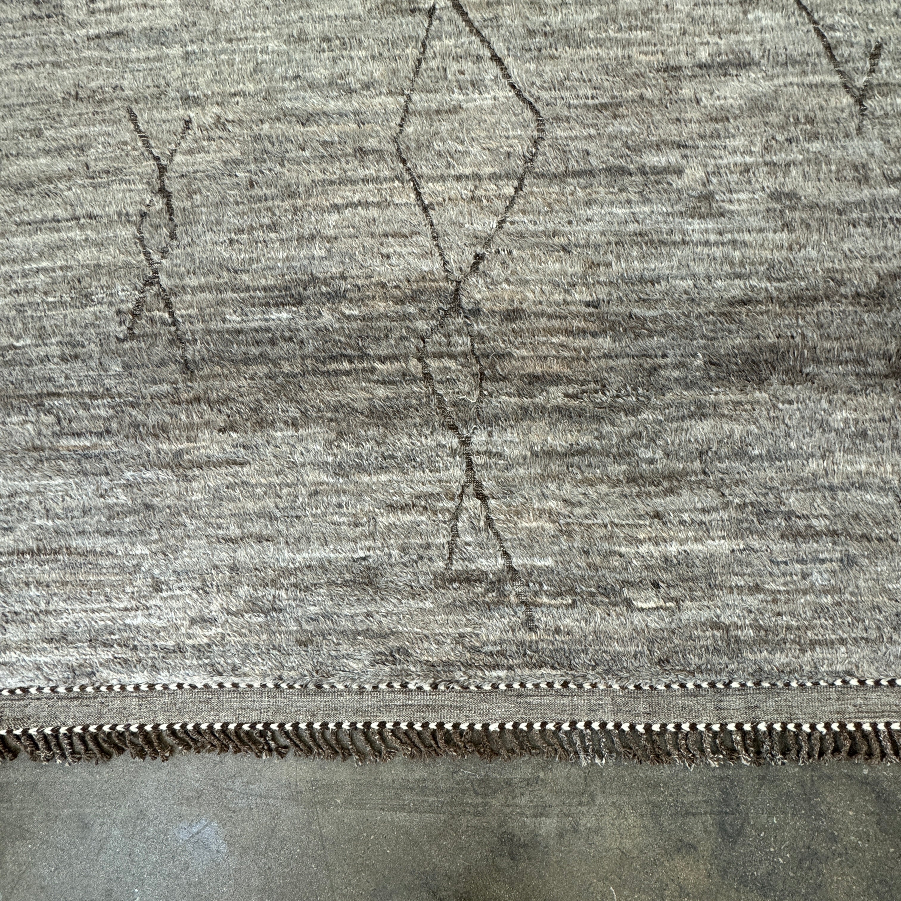 The Mehraban Gilavar Rug (13' x 15'.5") by Mehraban features handwoven, textured neutral tones, fringe tassels on the edges, and striped and patterned designs.