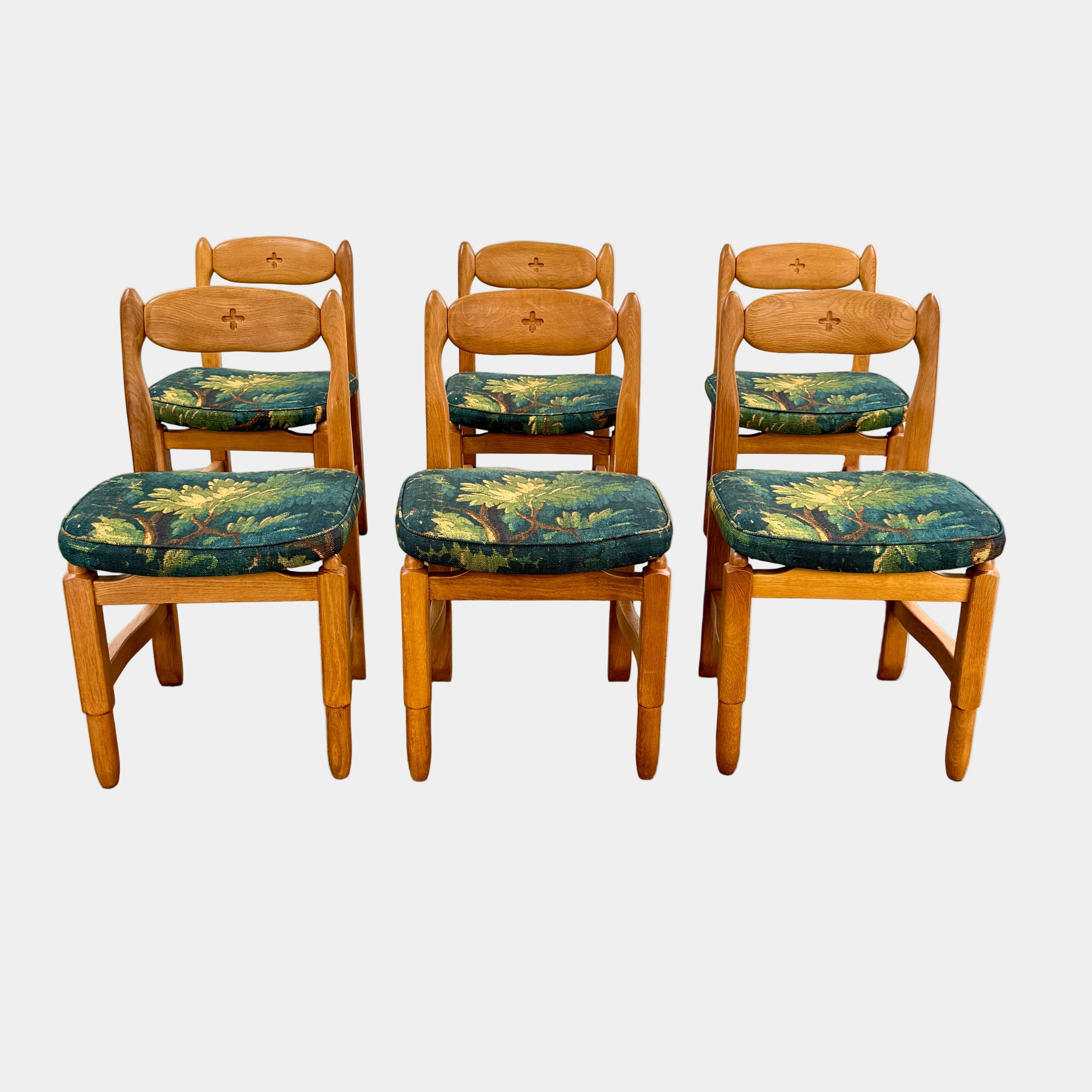 A set of 6 Vintage Votre Maison Guillerme Et Chambron dining chairs in French oak with curved backs and green floral upholstery are shown in two rows of three, highlighting postwar modernist elegance against a white background.