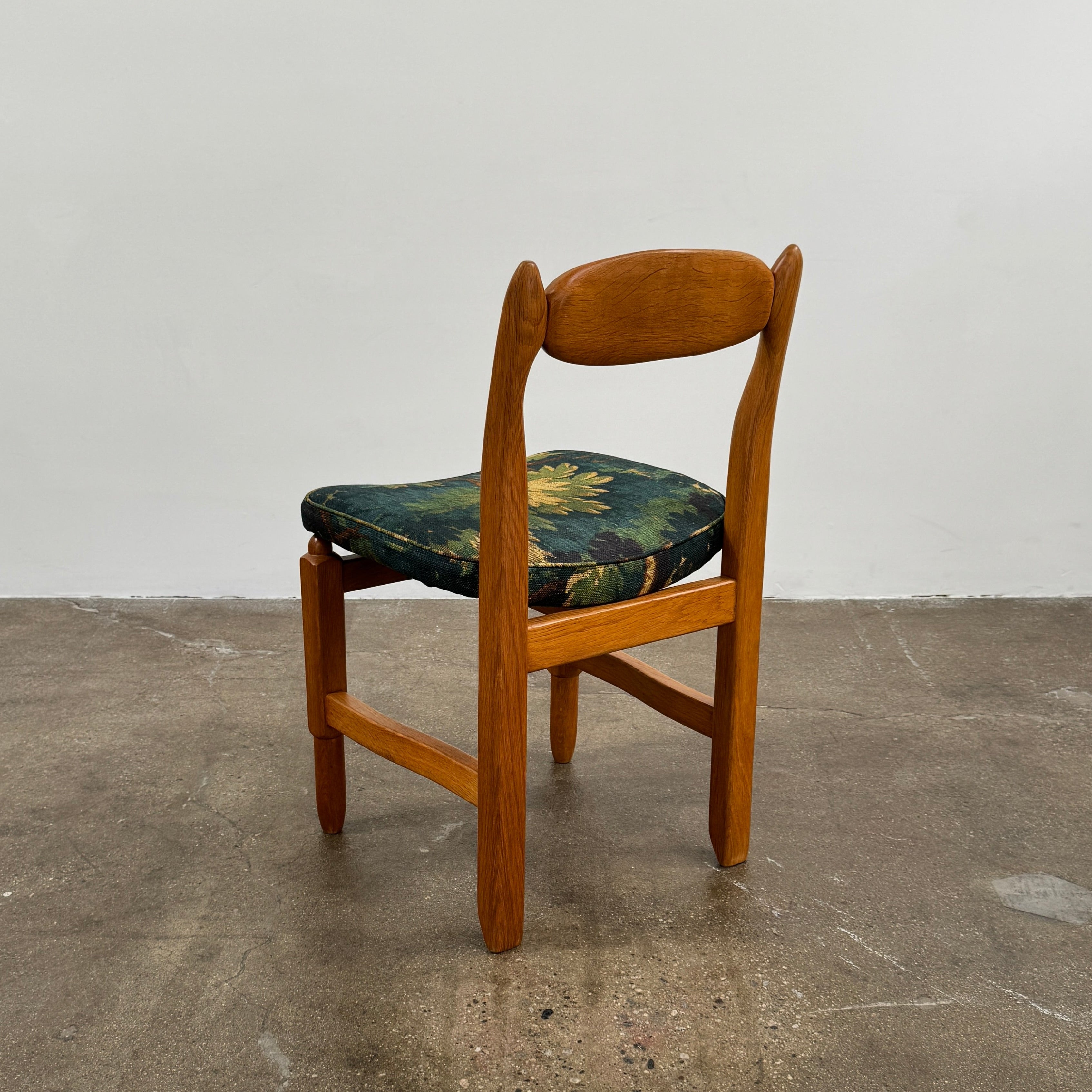 A set of 6 Vintage Votre Maison Guillerme Et Chambron dining chairs in French oak with curved backs and green floral upholstery are shown in two rows of three, highlighting postwar modernist elegance against a white background.