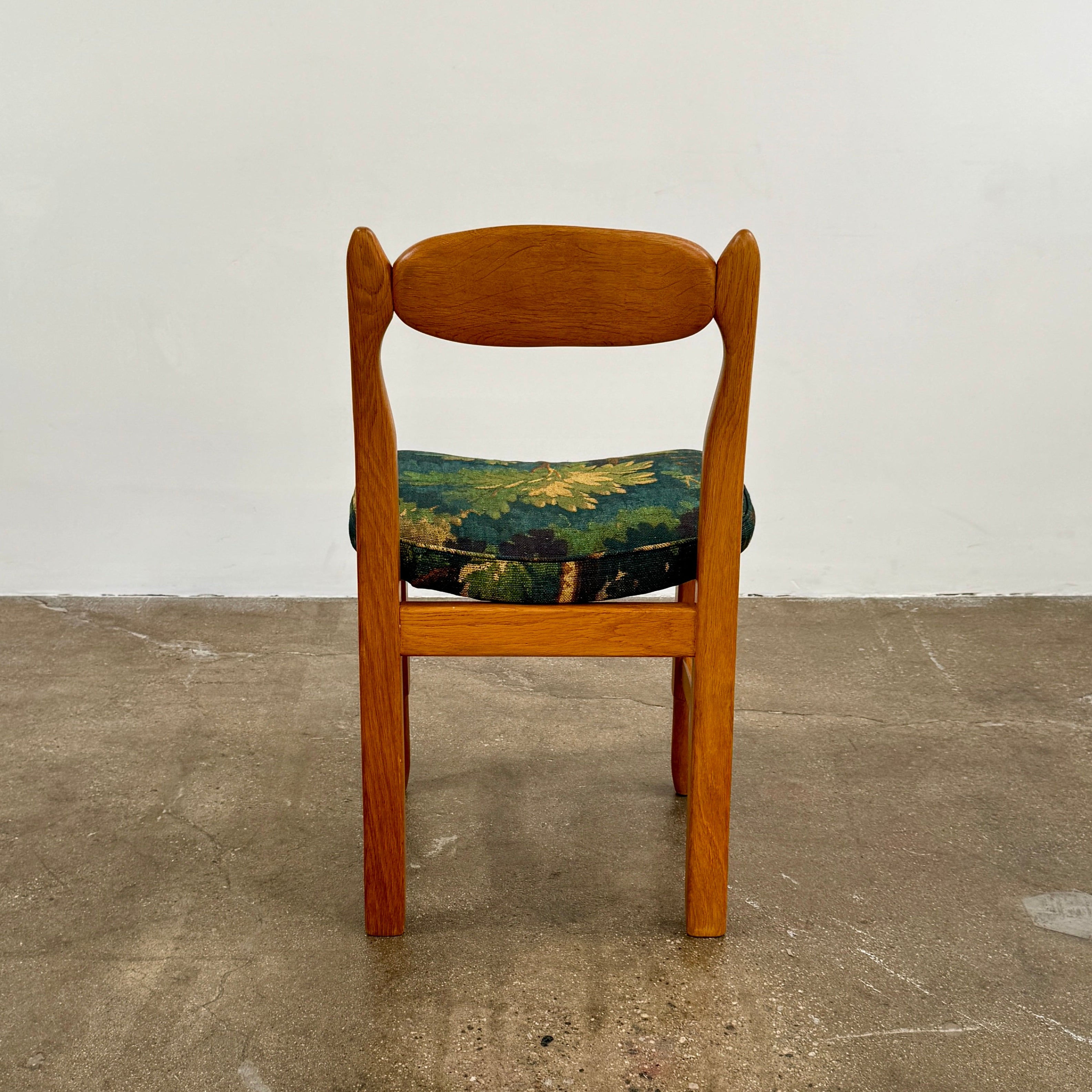 A set of 6 Vintage Votre Maison Guillerme Et Chambron dining chairs in French oak with curved backs and green floral upholstery are shown in two rows of three, highlighting postwar modernist elegance against a white background.