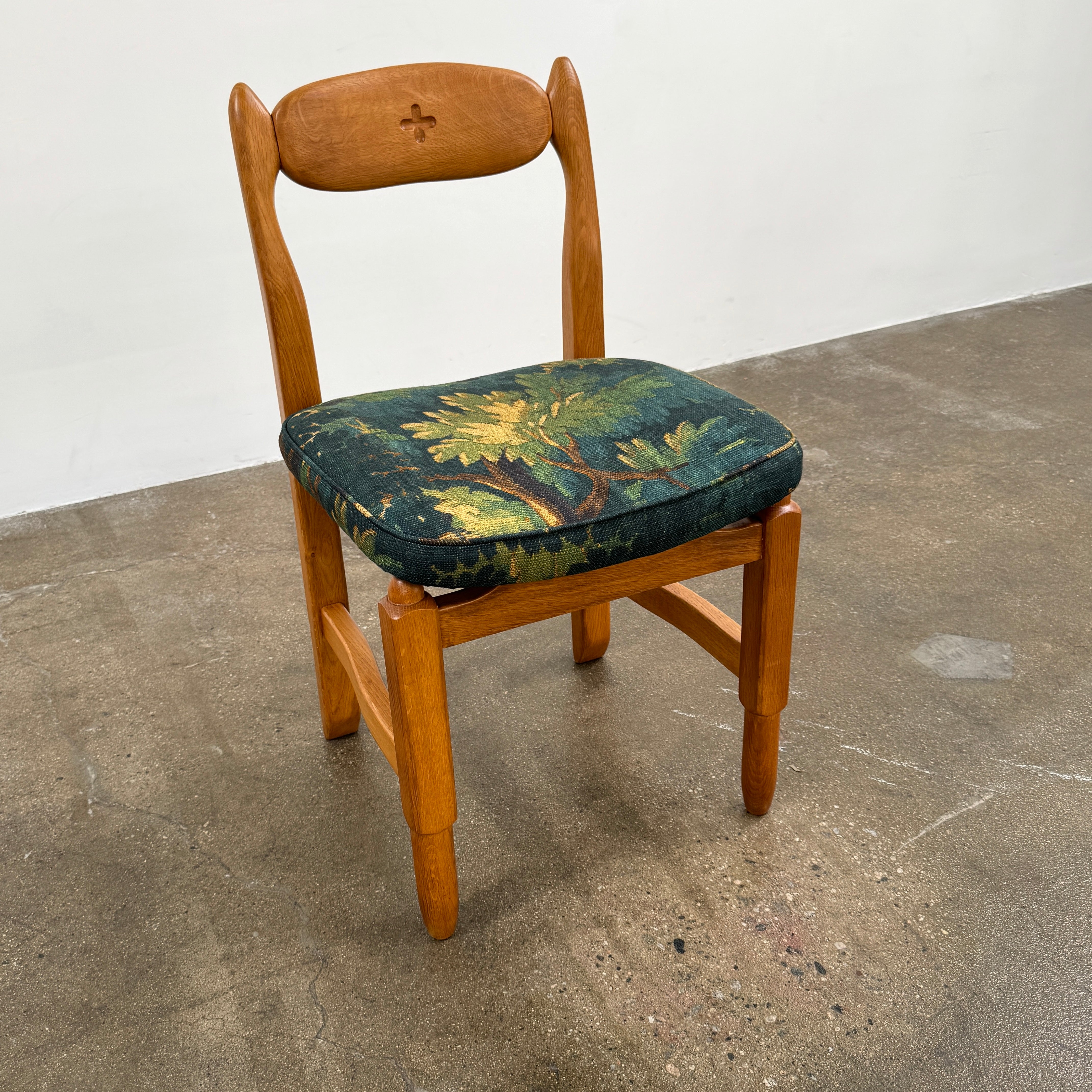 A set of 6 Vintage Votre Maison Guillerme Et Chambron dining chairs in French oak with curved backs and green floral upholstery are shown in two rows of three, highlighting postwar modernist elegance against a white background.