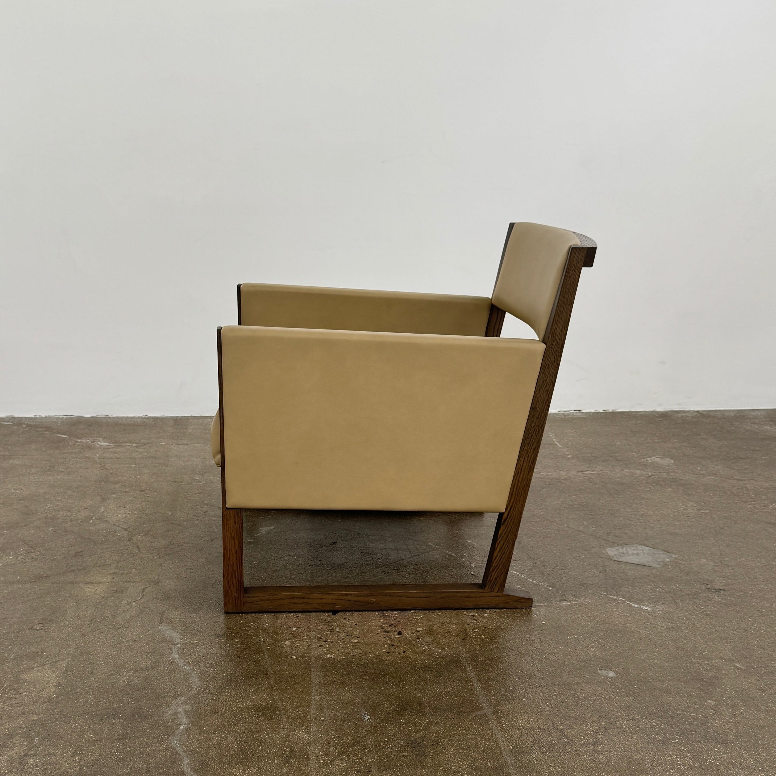 The Maxalto Musa Armchair features a light brown top-grain leather seat and backrest, gray oak wooden frame, and square armrests, set against a plain white background.