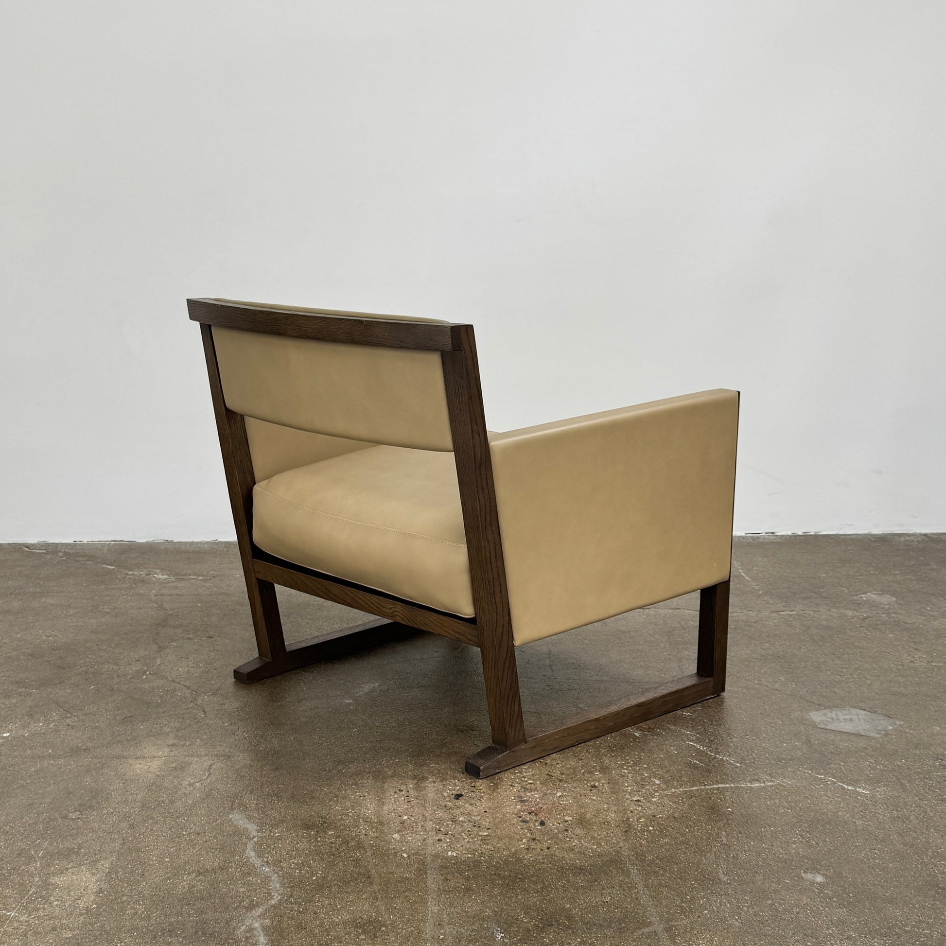 The Maxalto Musa Armchair features a light brown top-grain leather seat and backrest, gray oak wooden frame, and square armrests, set against a plain white background.