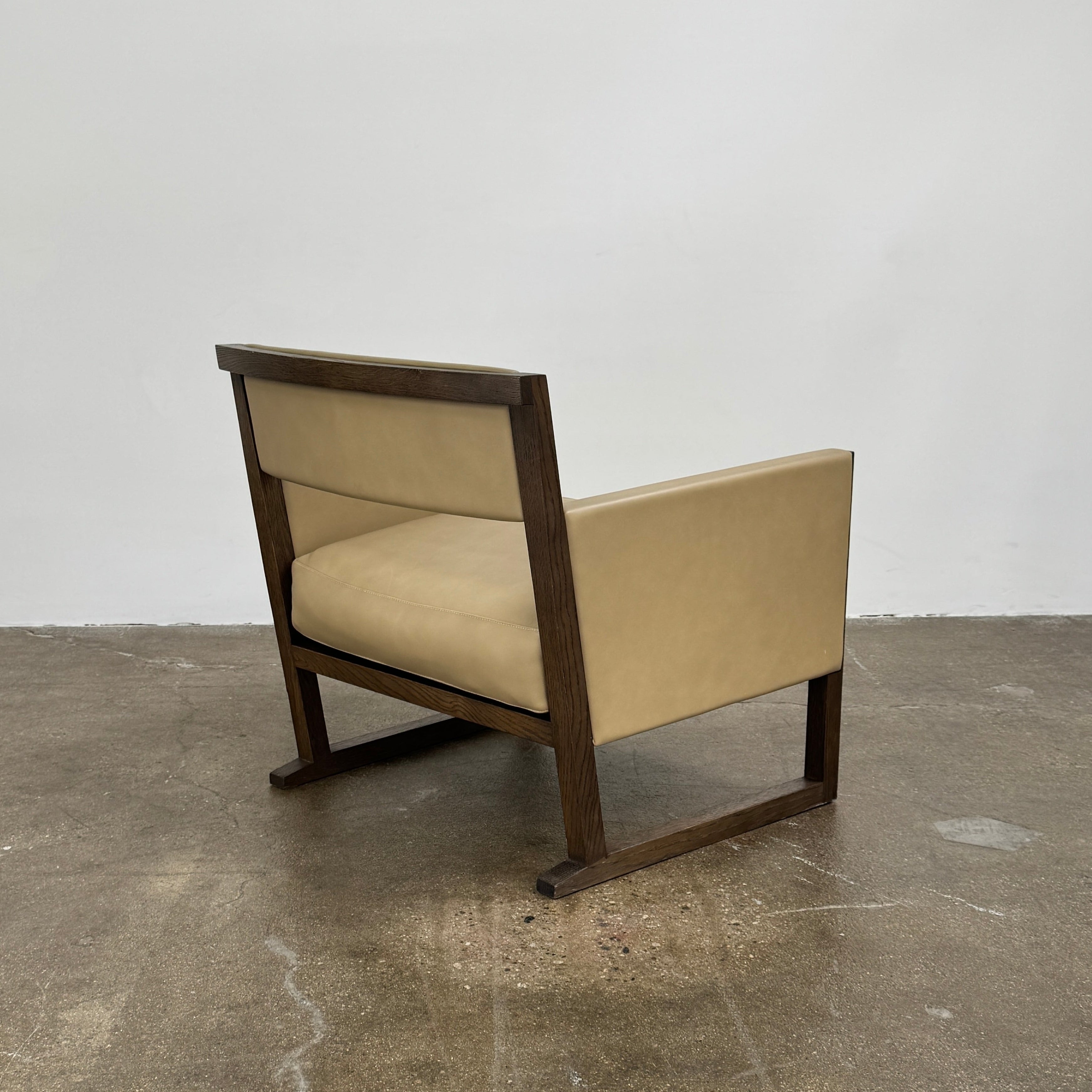 The Maxalto Musa Armchair features a light brown top-grain leather seat and backrest, gray oak wooden frame, and square armrests, set against a plain white background.