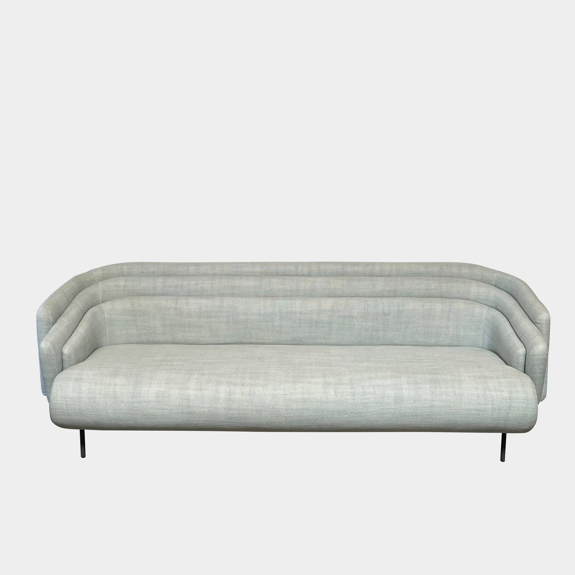 The Delcourt Collection Hug Sofa from the Delcourt Collection offers customizable fabric choices, including a light blue option, and is supported by sleek black legs.