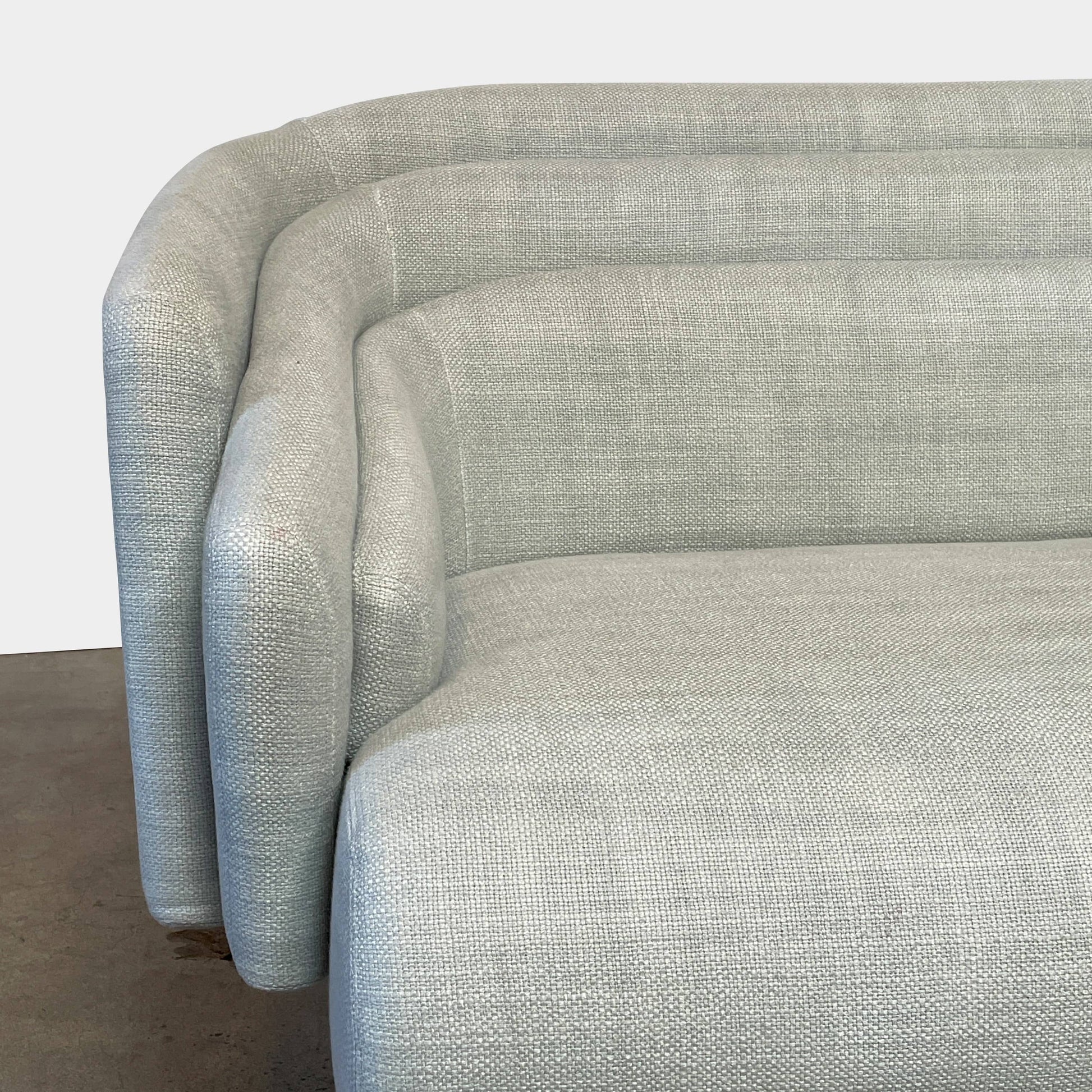 The Delcourt Collection Hug Sofa from the Delcourt Collection offers customizable fabric choices, including a light blue option, and is supported by sleek black legs.