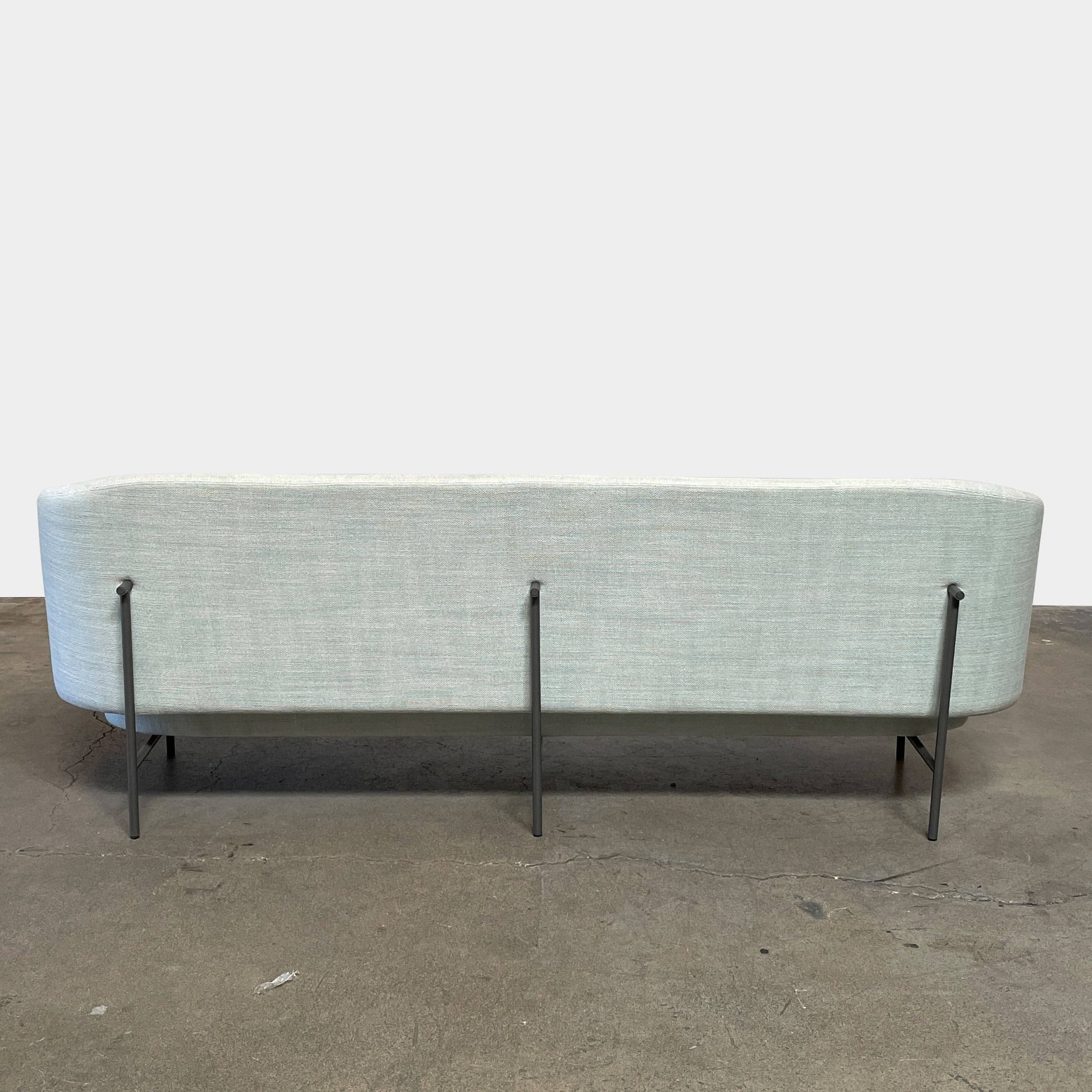 The Delcourt Collection Hug Sofa from the Delcourt Collection offers customizable fabric choices, including a light blue option, and is supported by sleek black legs.